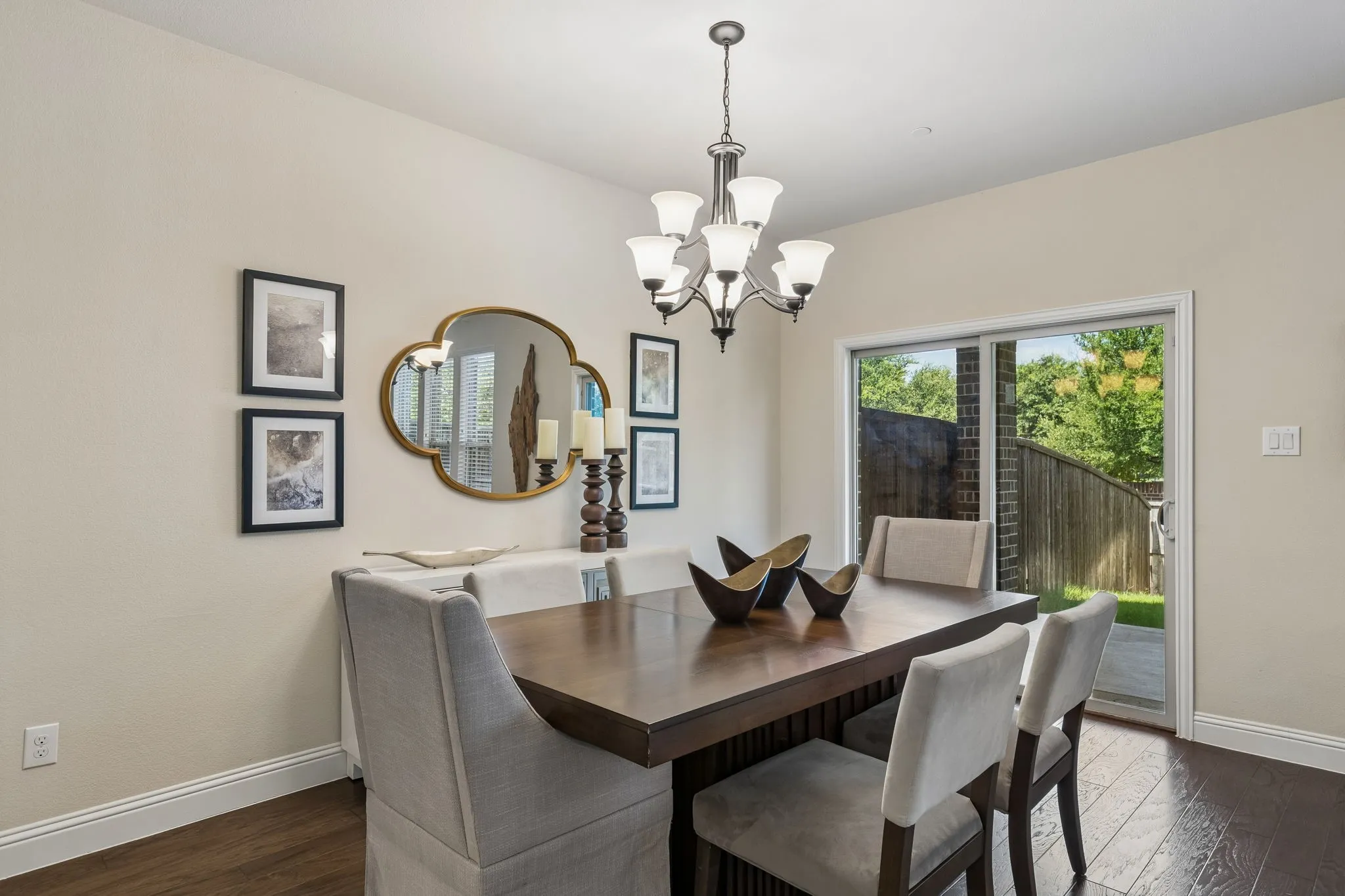 Dining area with wood-finish flooring, a contemporary multi-light chandelier, and a sliding glass door providing exterior access