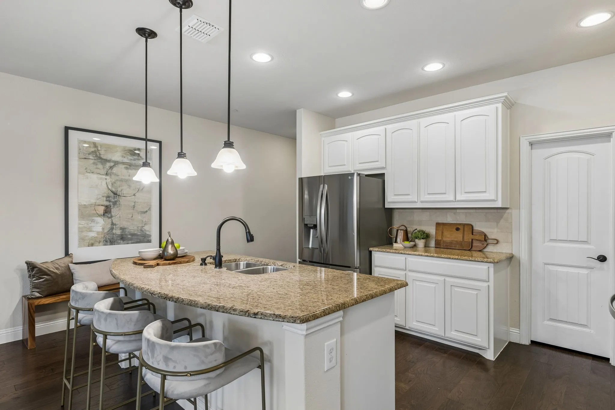 Kitchen featuring a curved island with granite countertop, stainless steel double-basin sink, and matte black faucet