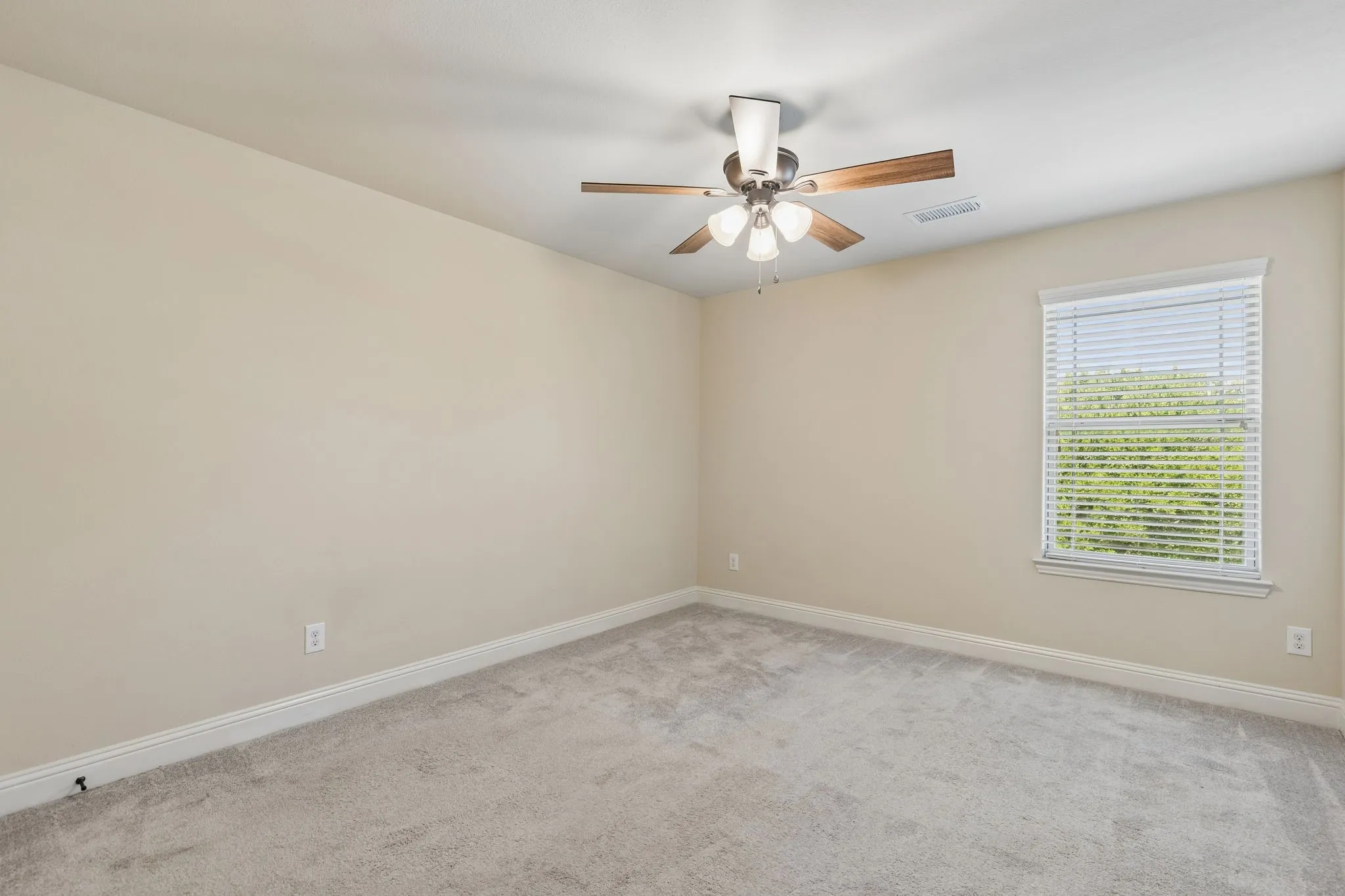 Bedroom featuring light neutral wall paint, gray carpet flooring, white baseboards, a window with white blinds, and a ceiling fan with wood-look blades