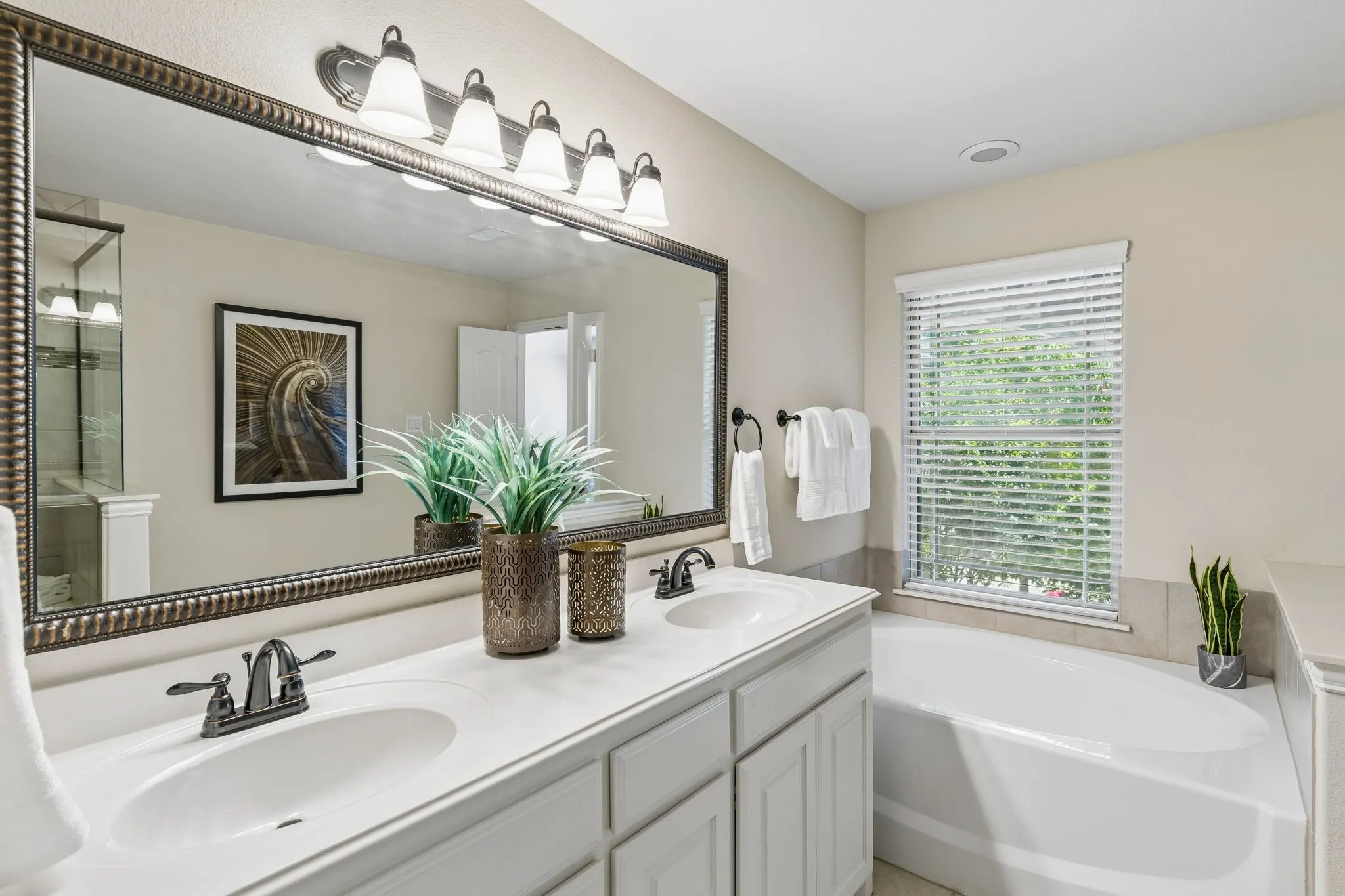 Dual vanity with undermount sinks, bronze finish fixtures, and an oversized framed mirror