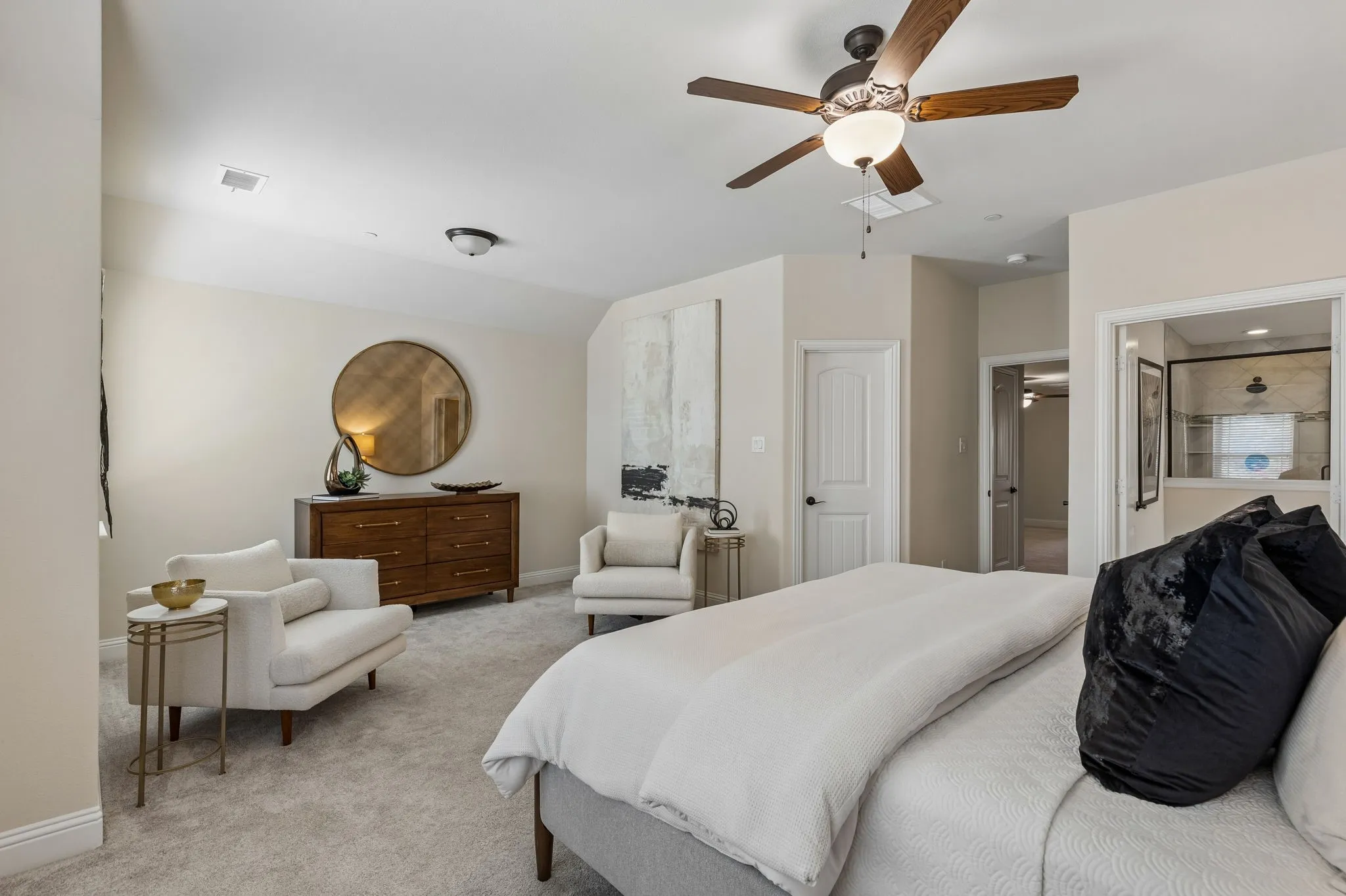 Spacious bedroom featuring light-colored walls and plush carpeting
