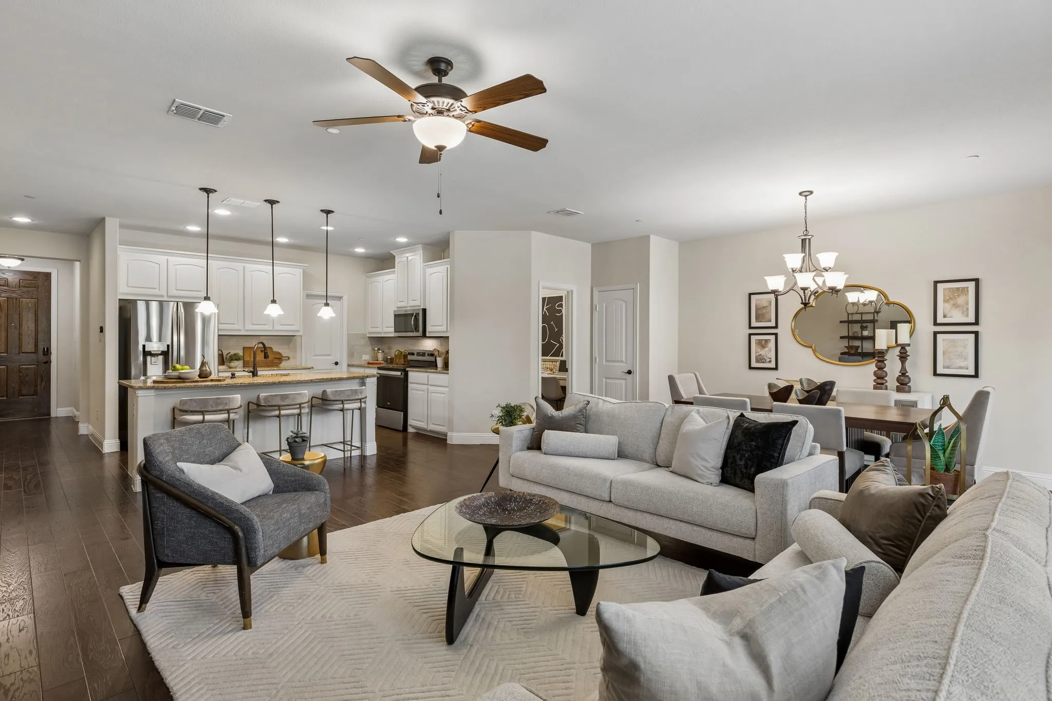 Expansive living area featuring wood-finish flooring, a ceiling fan with integrated lighting, and recessed lighting