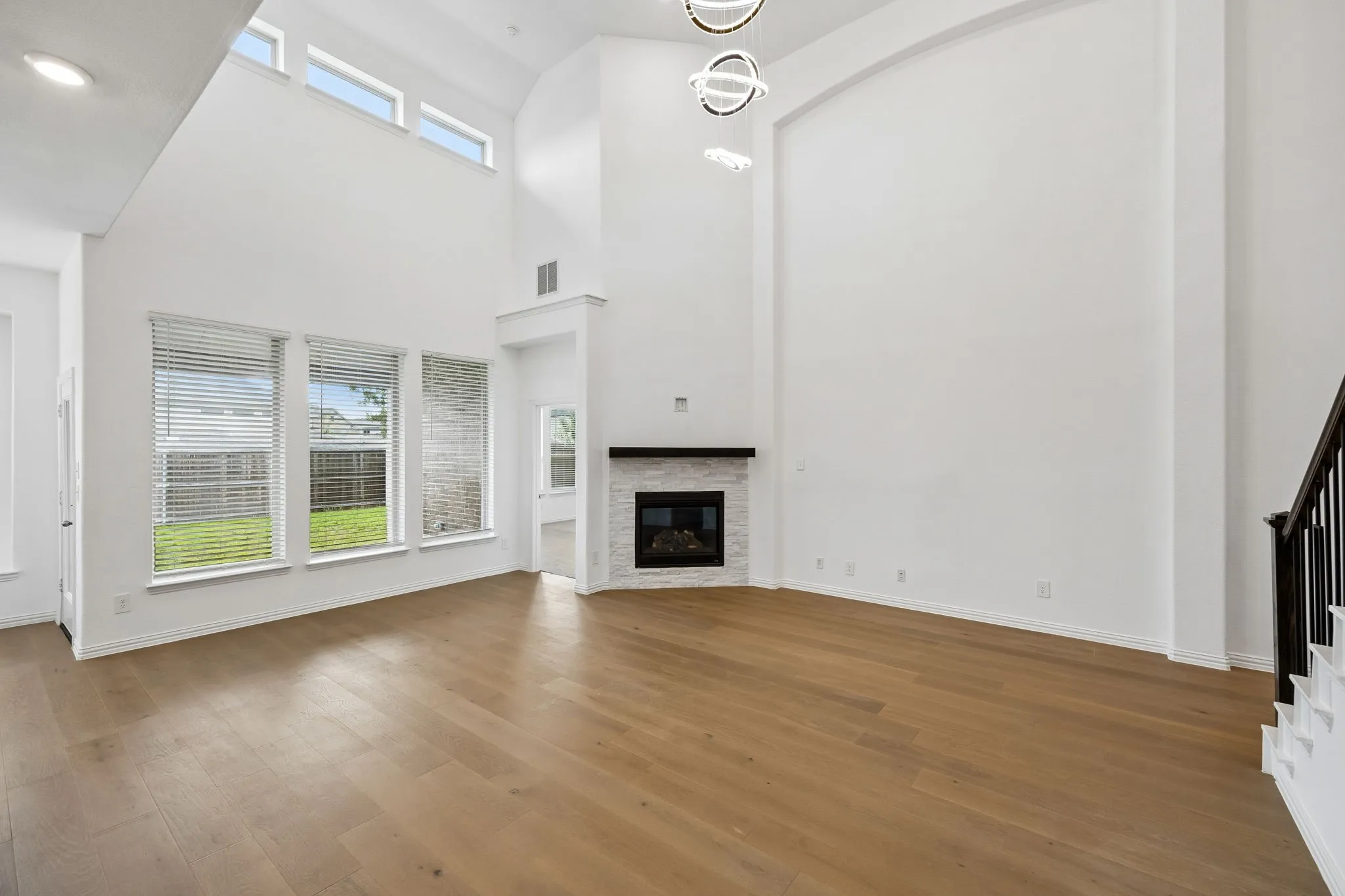 Great room featuring wood-finish flooring, a corner fireplace with a white stone surround, and an integrated mantle