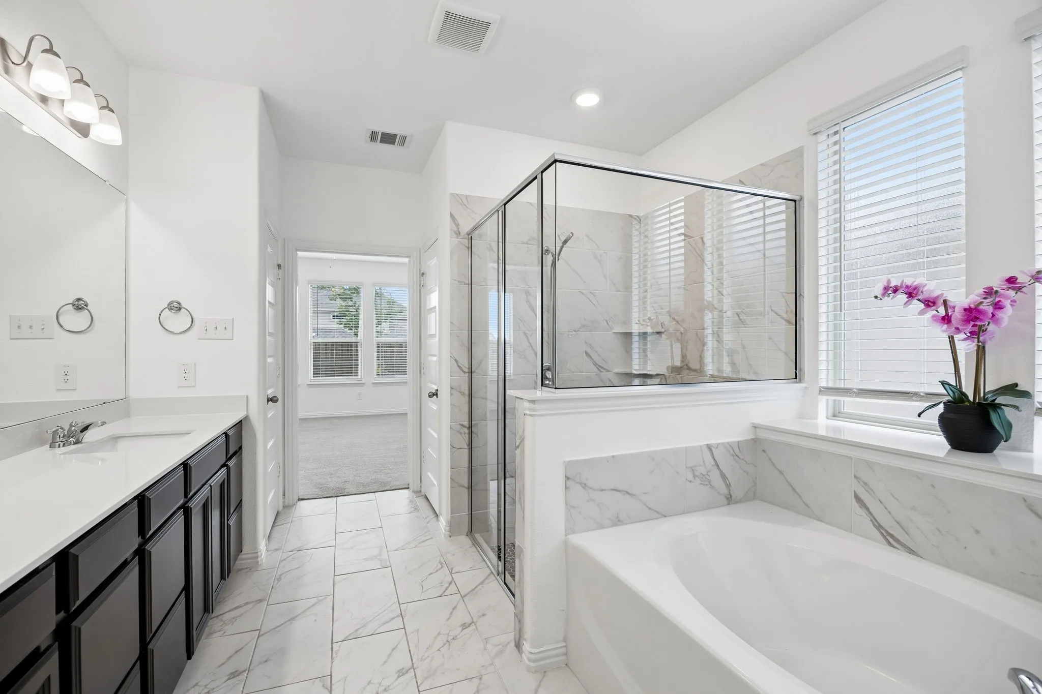 Bathroom featuring a double vanity with dark cabinetry, integrated sinks, and chrome fixtures