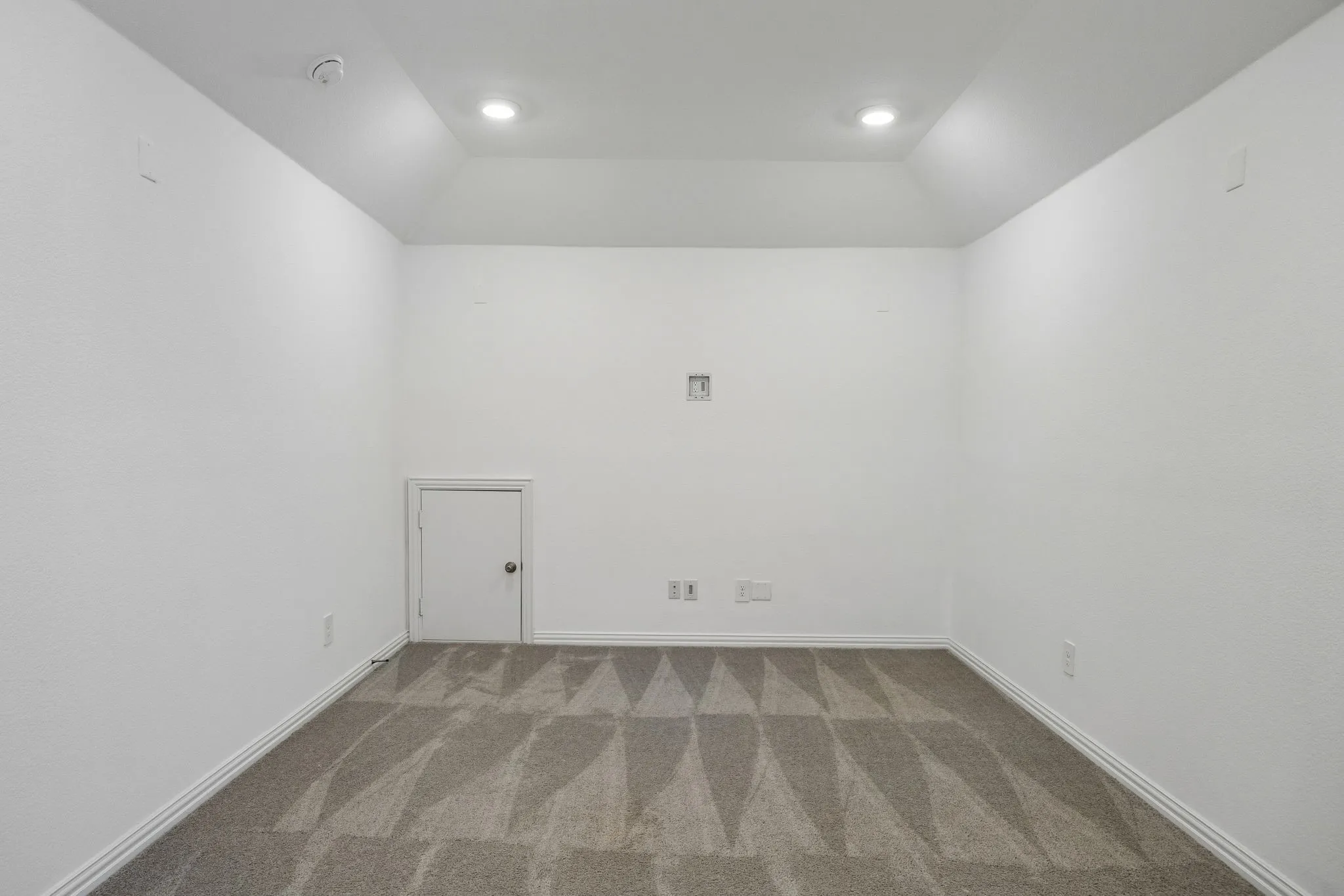 Recessed lighting illuminating a spacious room with patterned carpeting