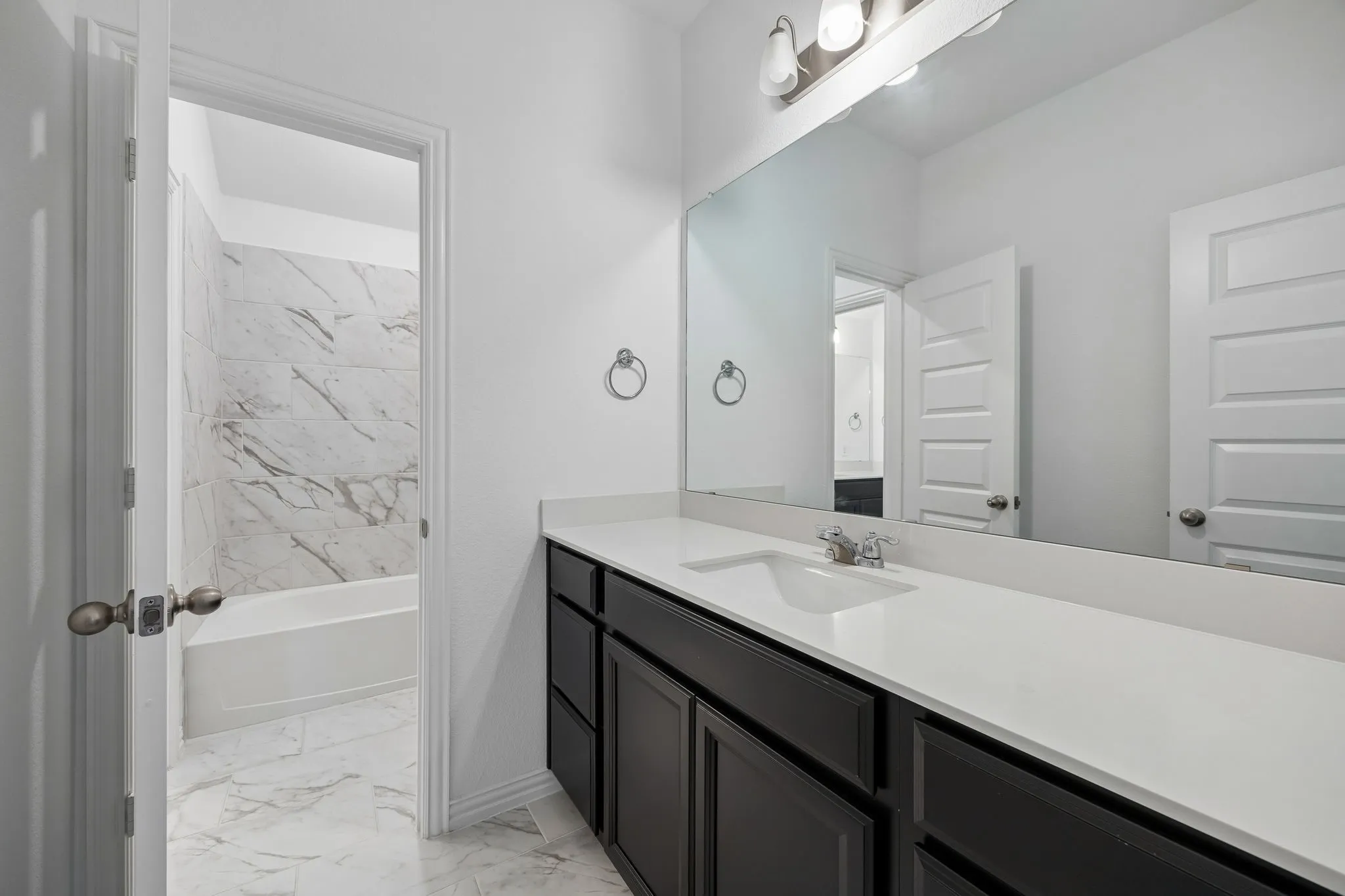 2nd floor secondary bath Double vanity with dark wood-finish cabinetry and light-toned countertops