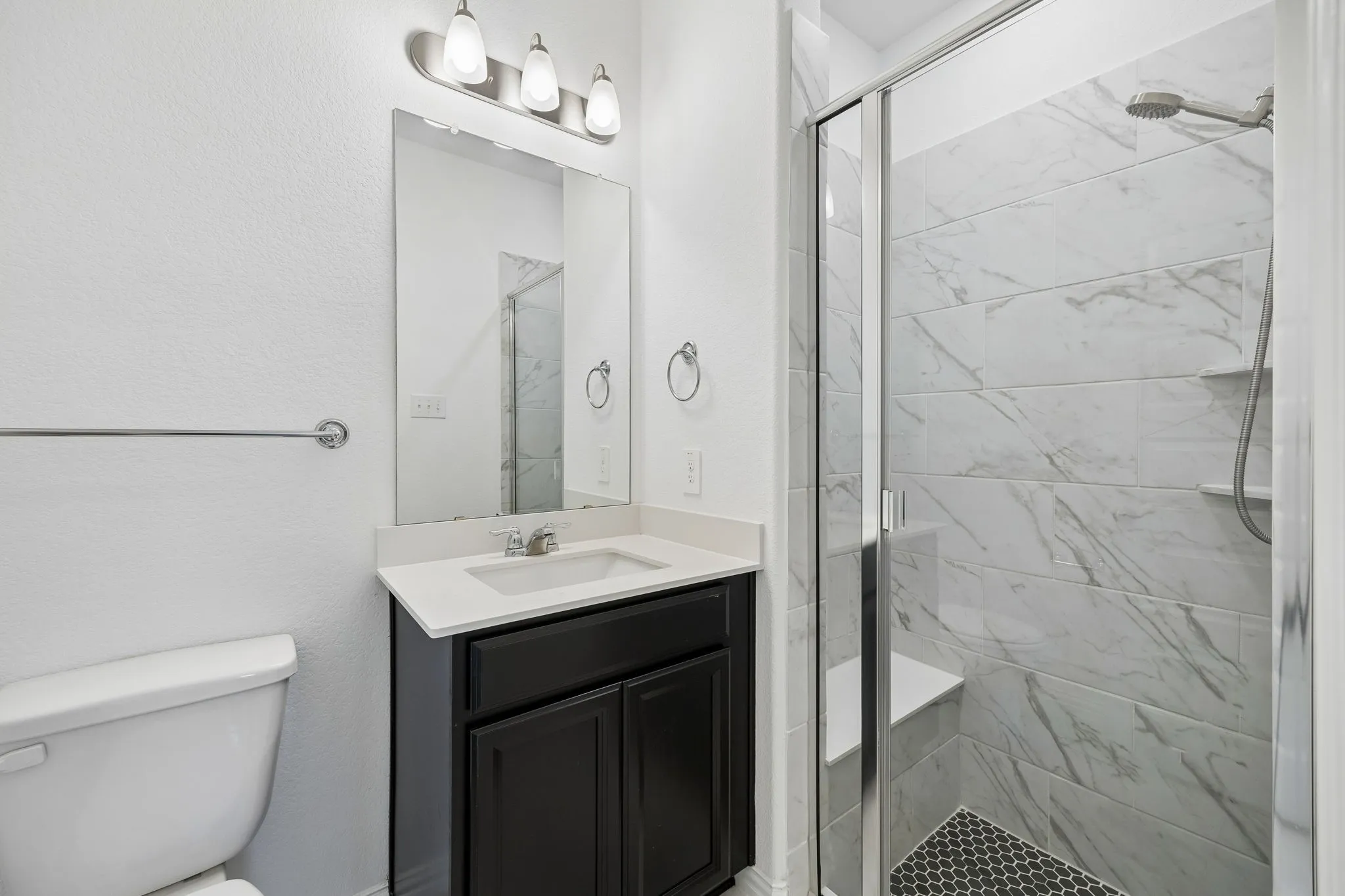 1st floor guest Bathroom featuring a dark wood-finish vanity with a light countertop, a rectangular mirror, and an overhead light fixture