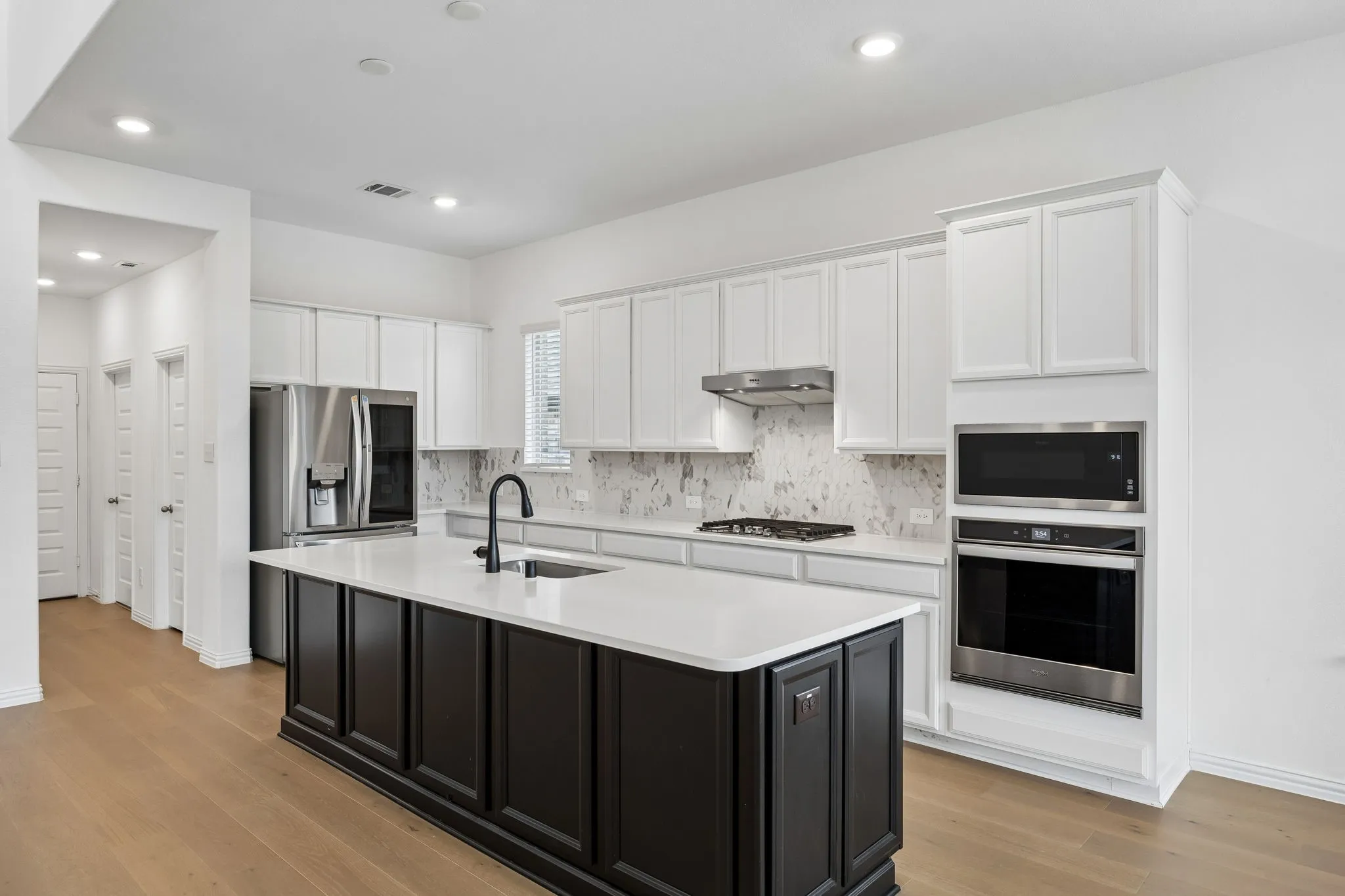 Contemporary kitchen featuring an island with a contrasting black base, white countertop, and integrated sink