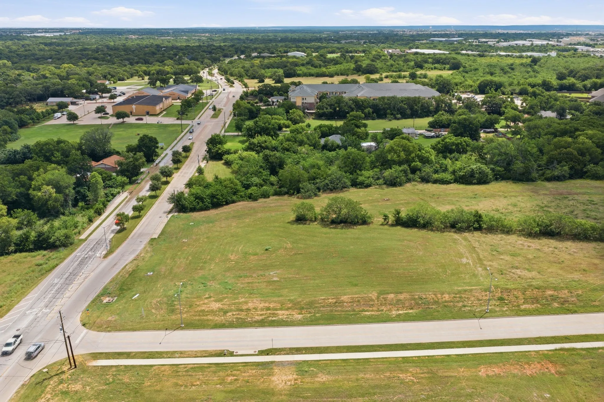 Expansive vacant lot featuring a grass field and a paved road frontage