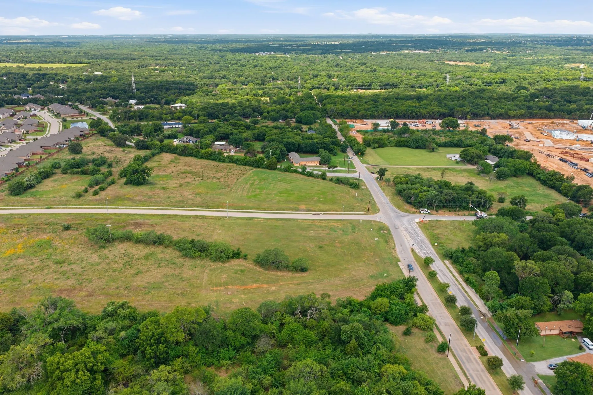 Expansive land parcel featuring existing road access and surrounding mature trees