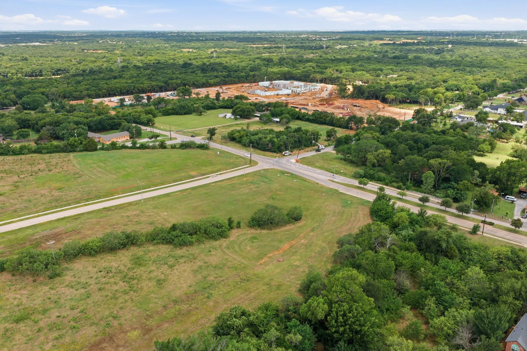 Expansive land parcel featuring existing roadways and surrounded by mature trees