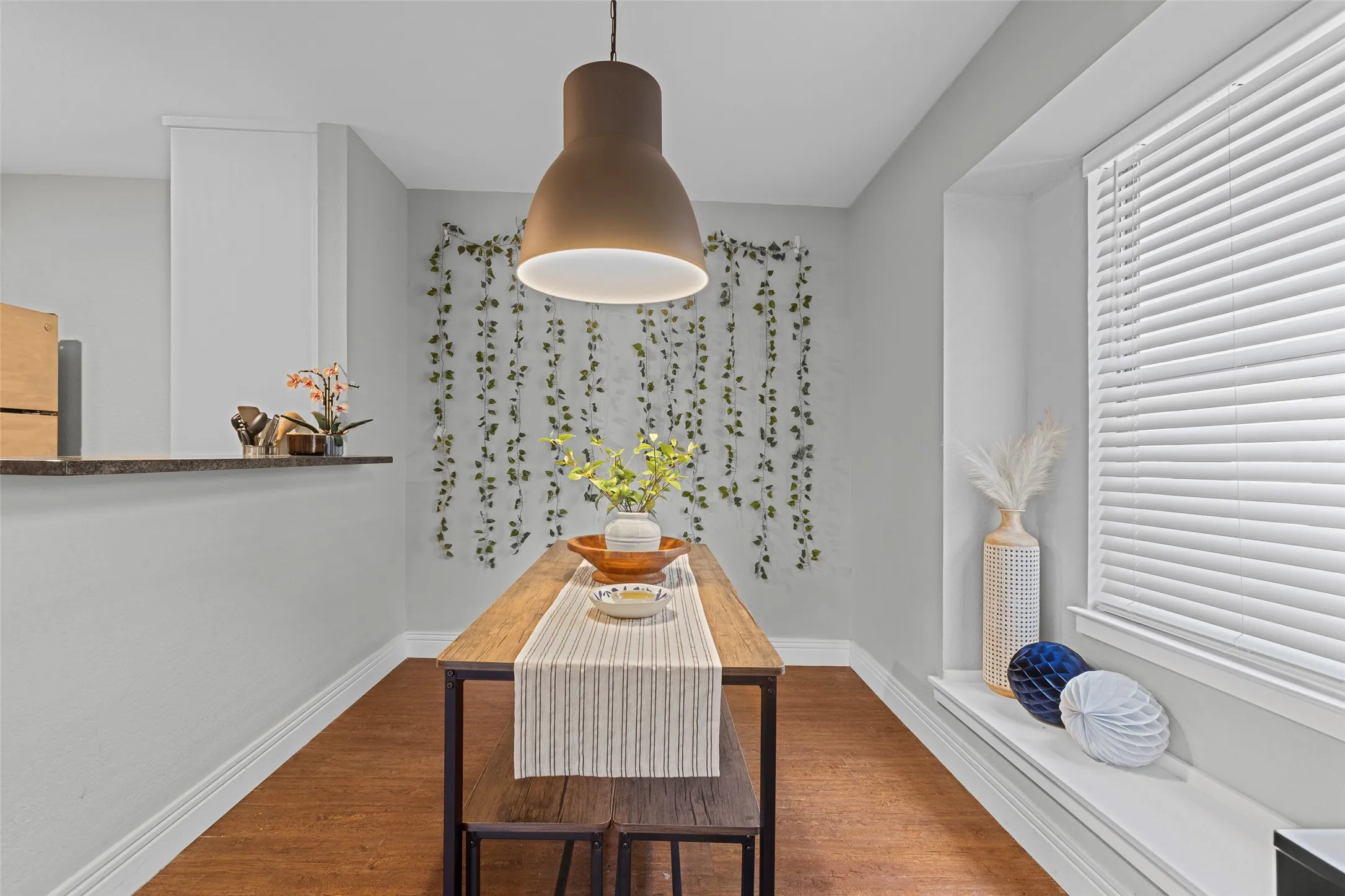 Dining area featuring wood-finish flooring, a built-in window ledge, and a modern pendant light fixture