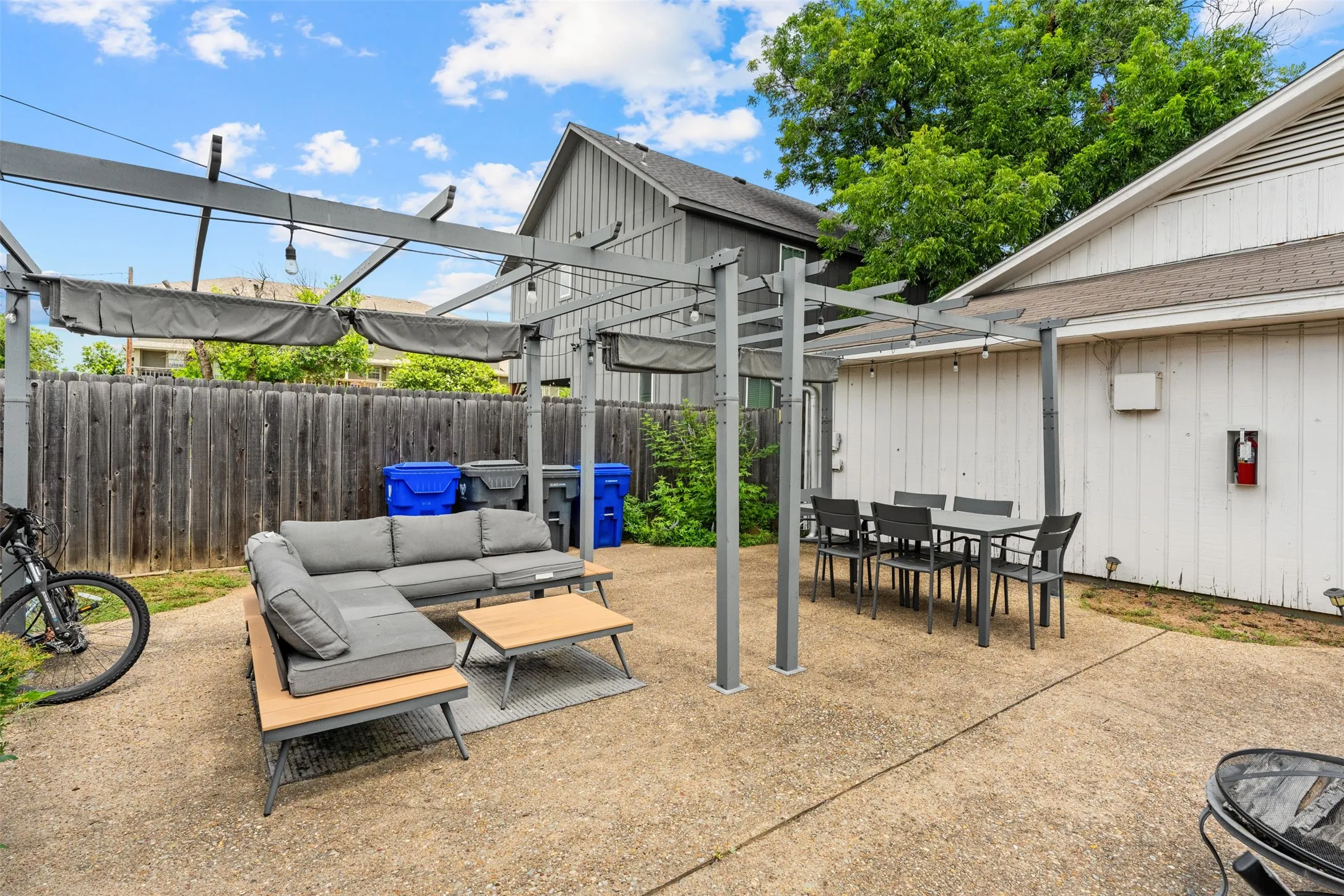 Spacious concrete patio featuring a metal pergola with retractable fabric canopies and string lighting