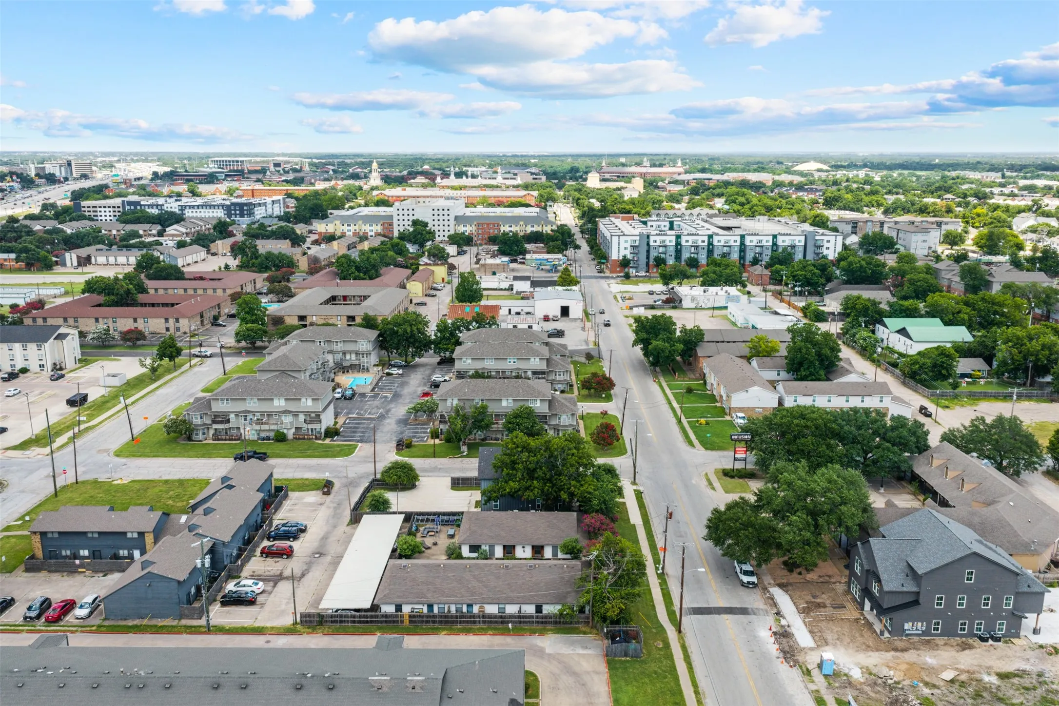 Aerial perspective showcasing a mixed-use neighborhood with diverse architectural styles, including multi-story residential buildings and commercial properties