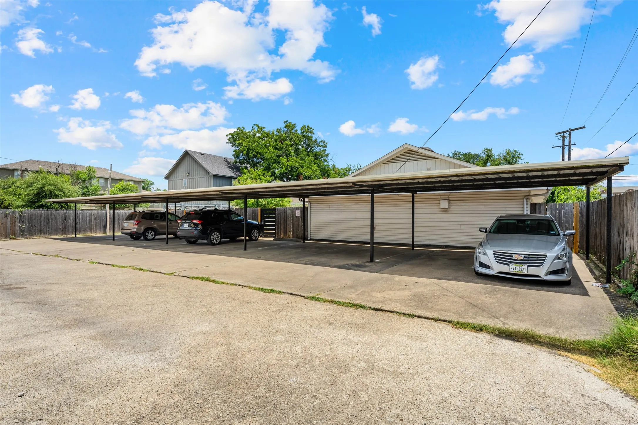 Multi-vehicle carport with a durable metal roof and concrete parking surface