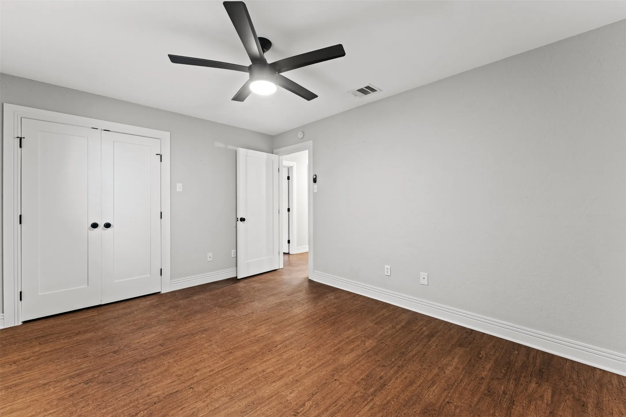 Room featuring wood-finish flooring, light grey painted walls, and white trim