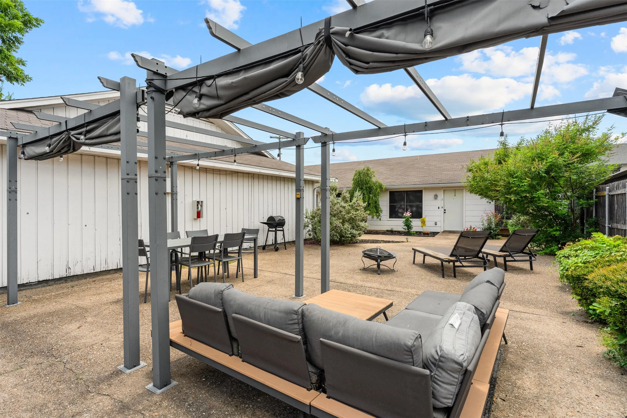 Expansive outdoor living area featuring a modern pergola with retractable canopies and string lighting