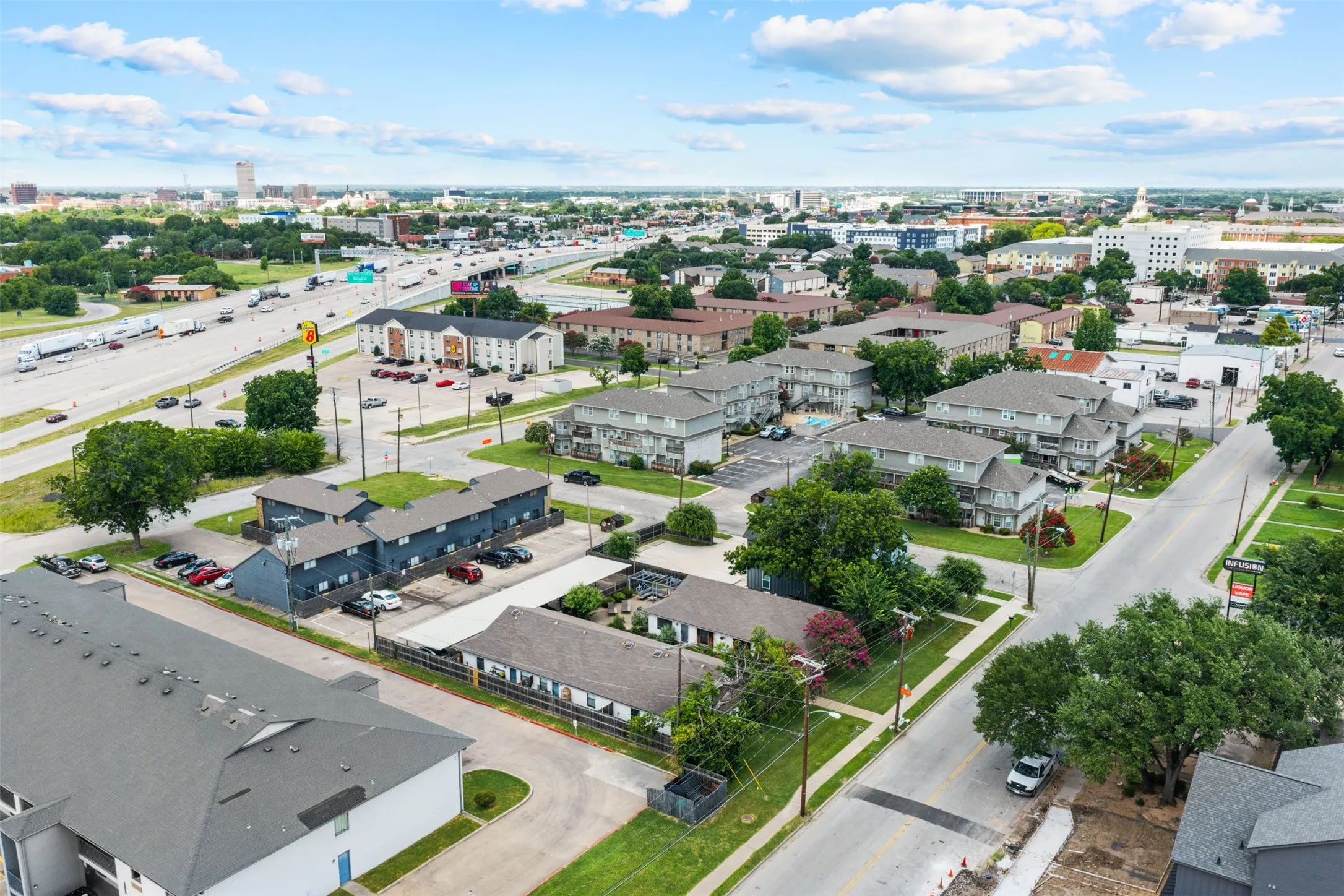 Aerial perspective showcasing a collection of multi-family buildings with ample surface parking