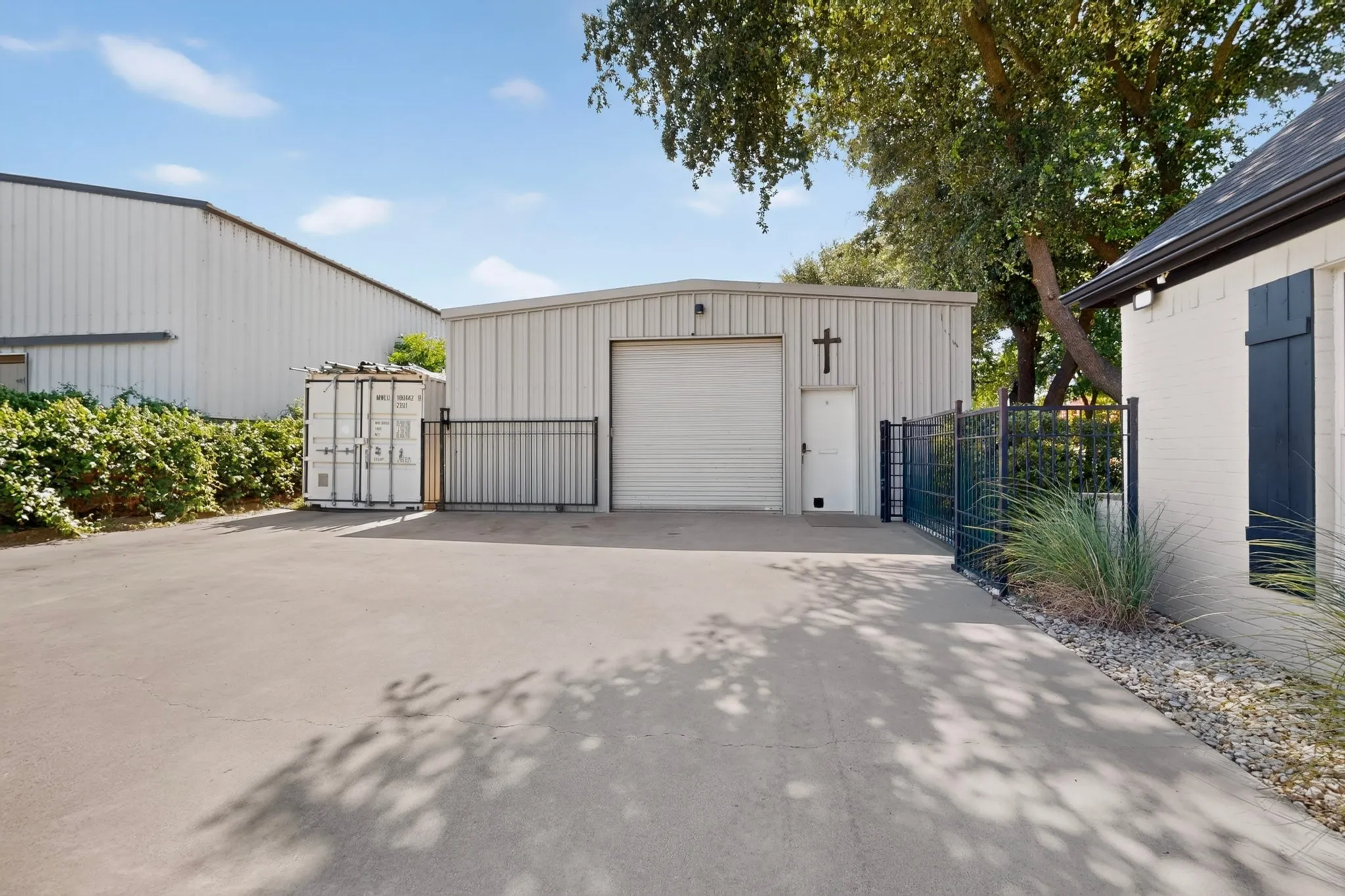 Expansive concrete paved area fronting a metal utility building with a roll-up door and separate entry