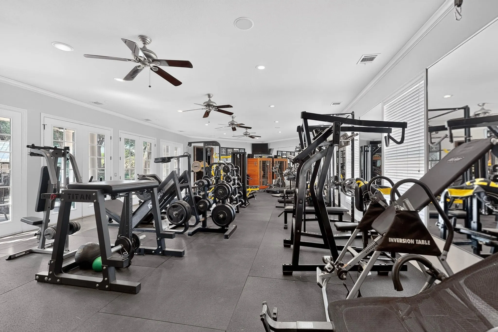 Dedicated fitness space featuring rubber flooring, multiple ceiling fans, recessed lighting, and mirrored walls