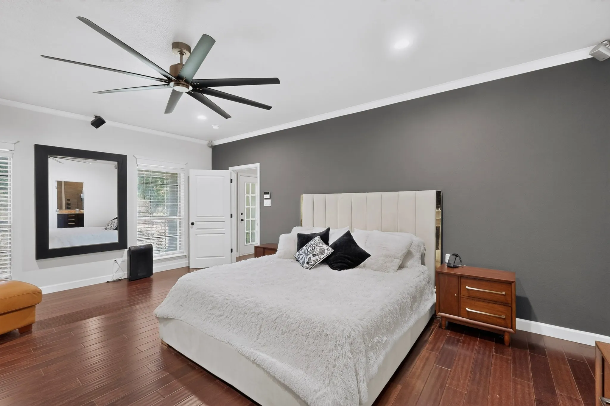 Spacious Primary Bedroom interior featuring wood-finish flooring, a contemporary ceiling fan, and crown molding
