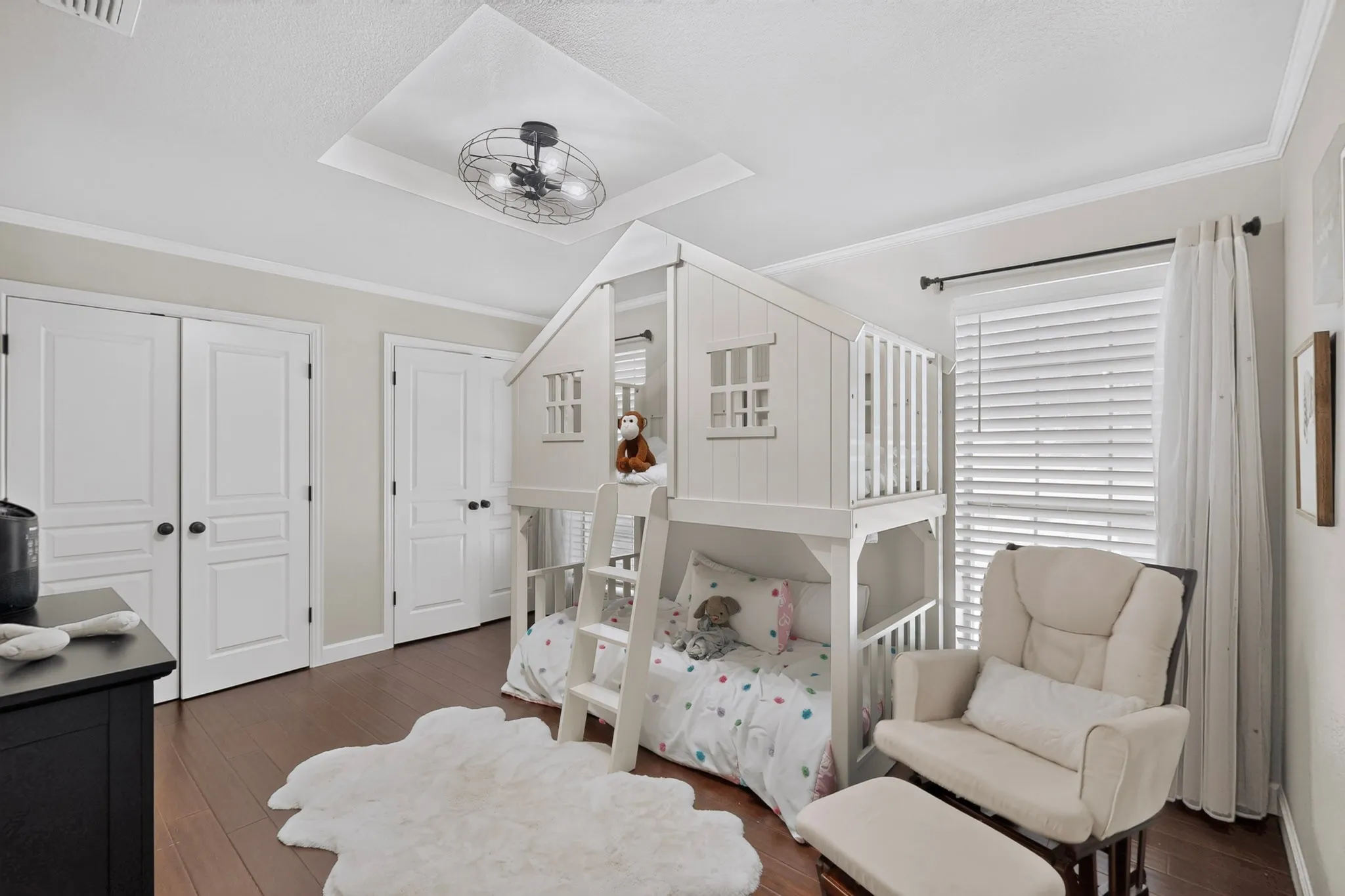 Recessed ceiling fan with a tray ceiling detail, multiple white paneled doors, wide plank wood-finish flooring, and white window blinds