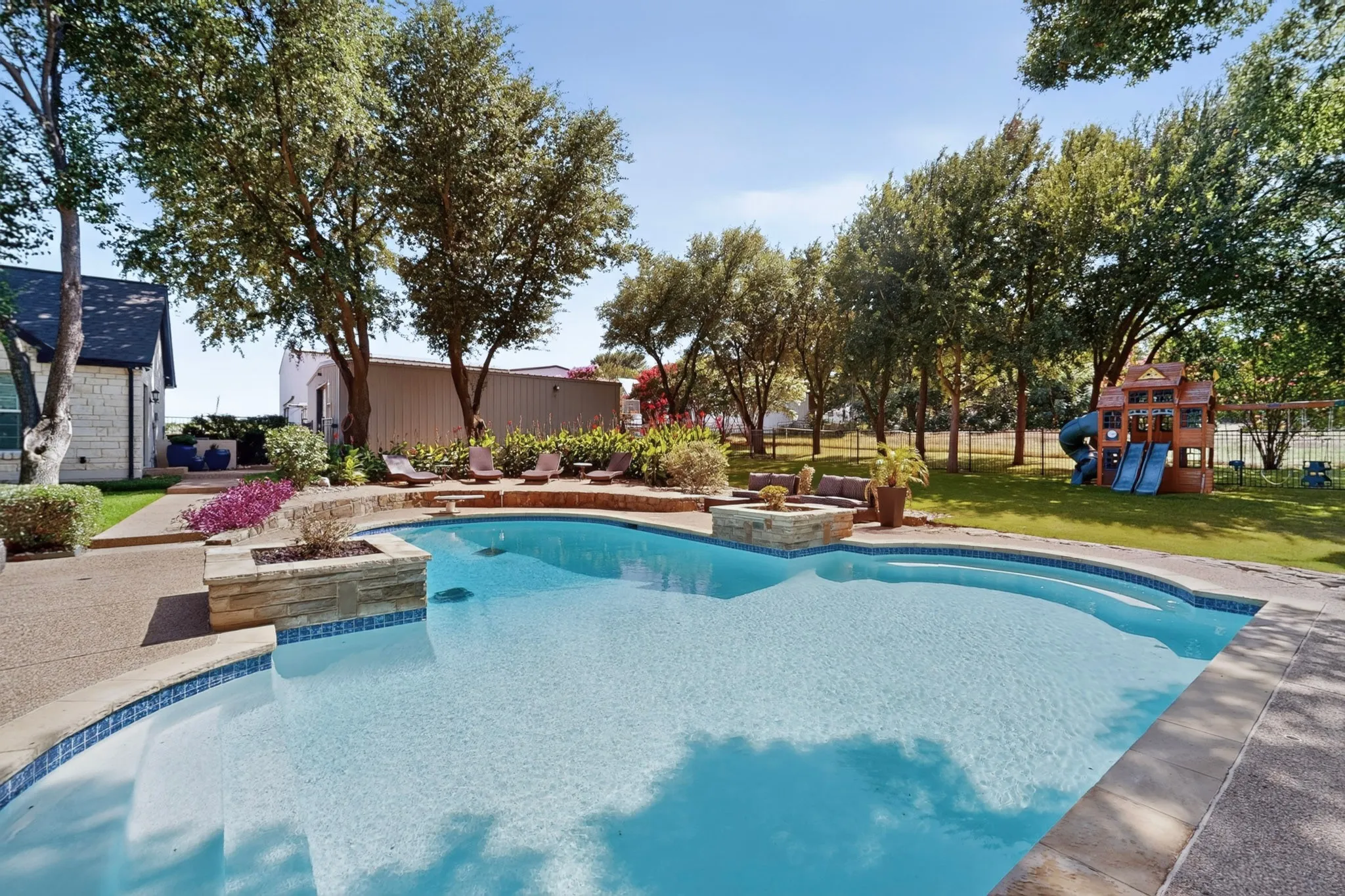 Curved swimming pool with stone coping and a mosaic tile border