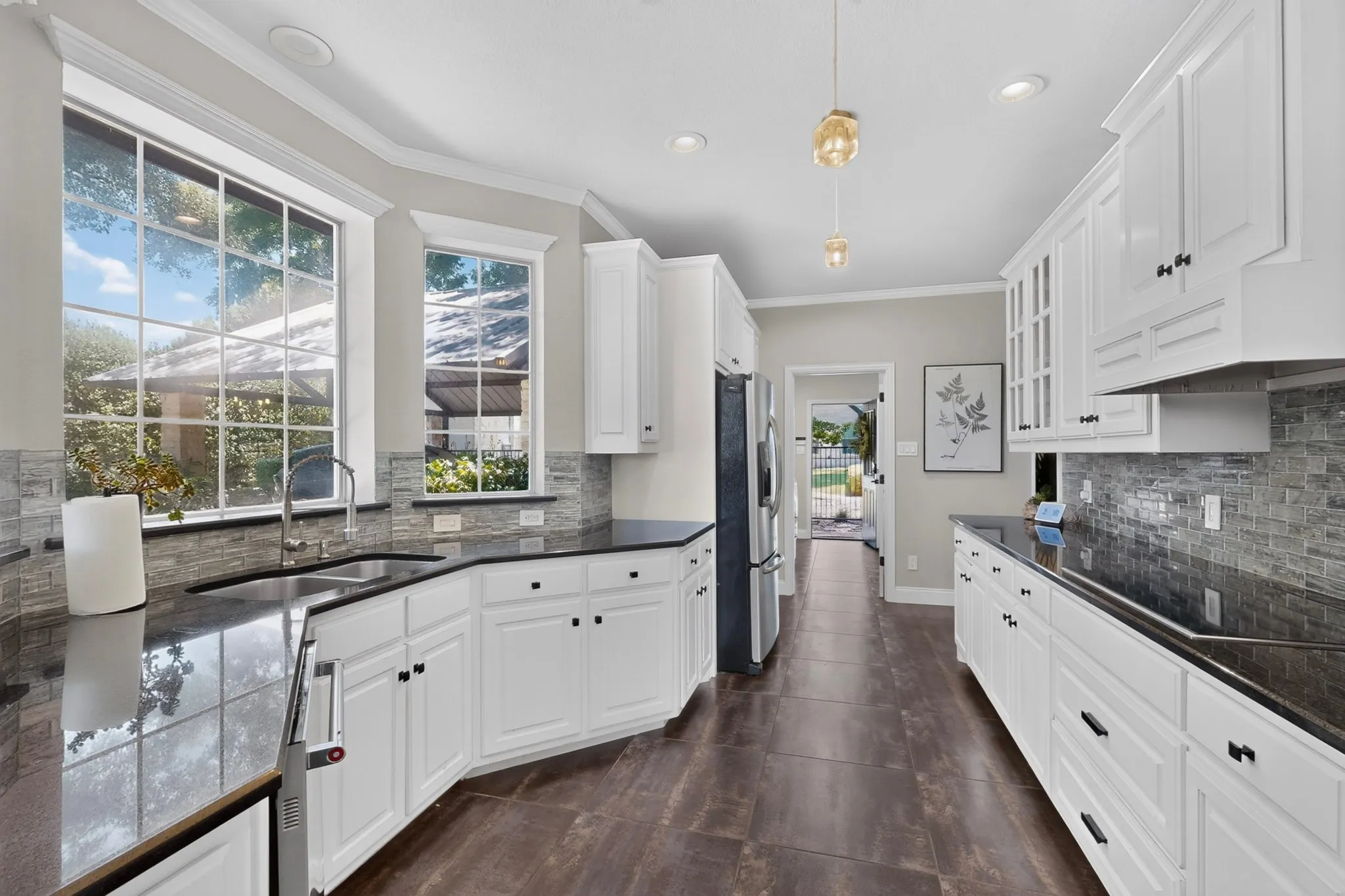 Galley kitchen featuring abundant white cabinetry, dark stone countertops, a mosaic tile backsplash, and dark wood-finish flooring