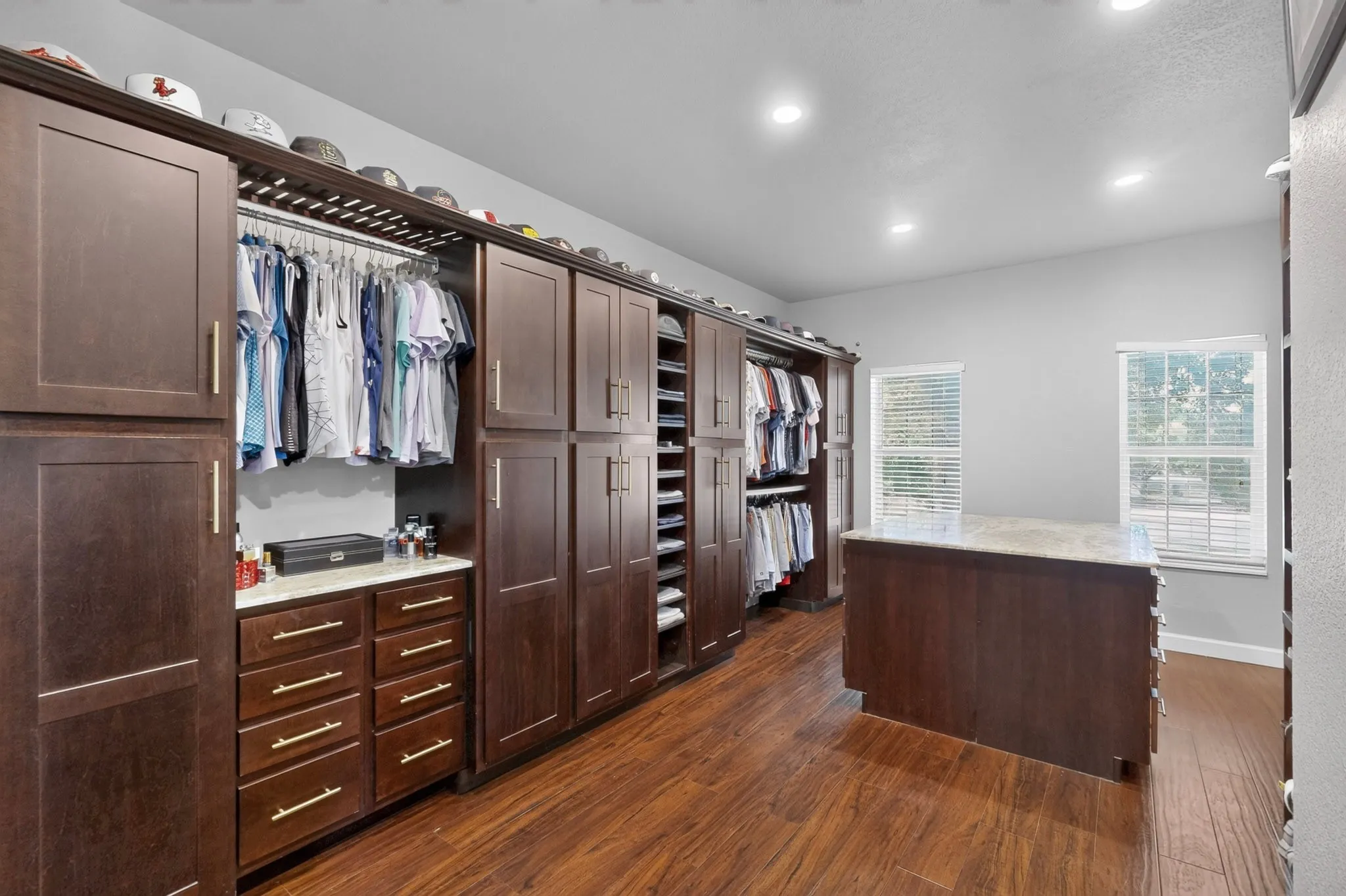 Custom walk-in closet featuring extensive dark wood cabinetry, integrated hanging storage, and multiple drawers with gold-toned hardware
