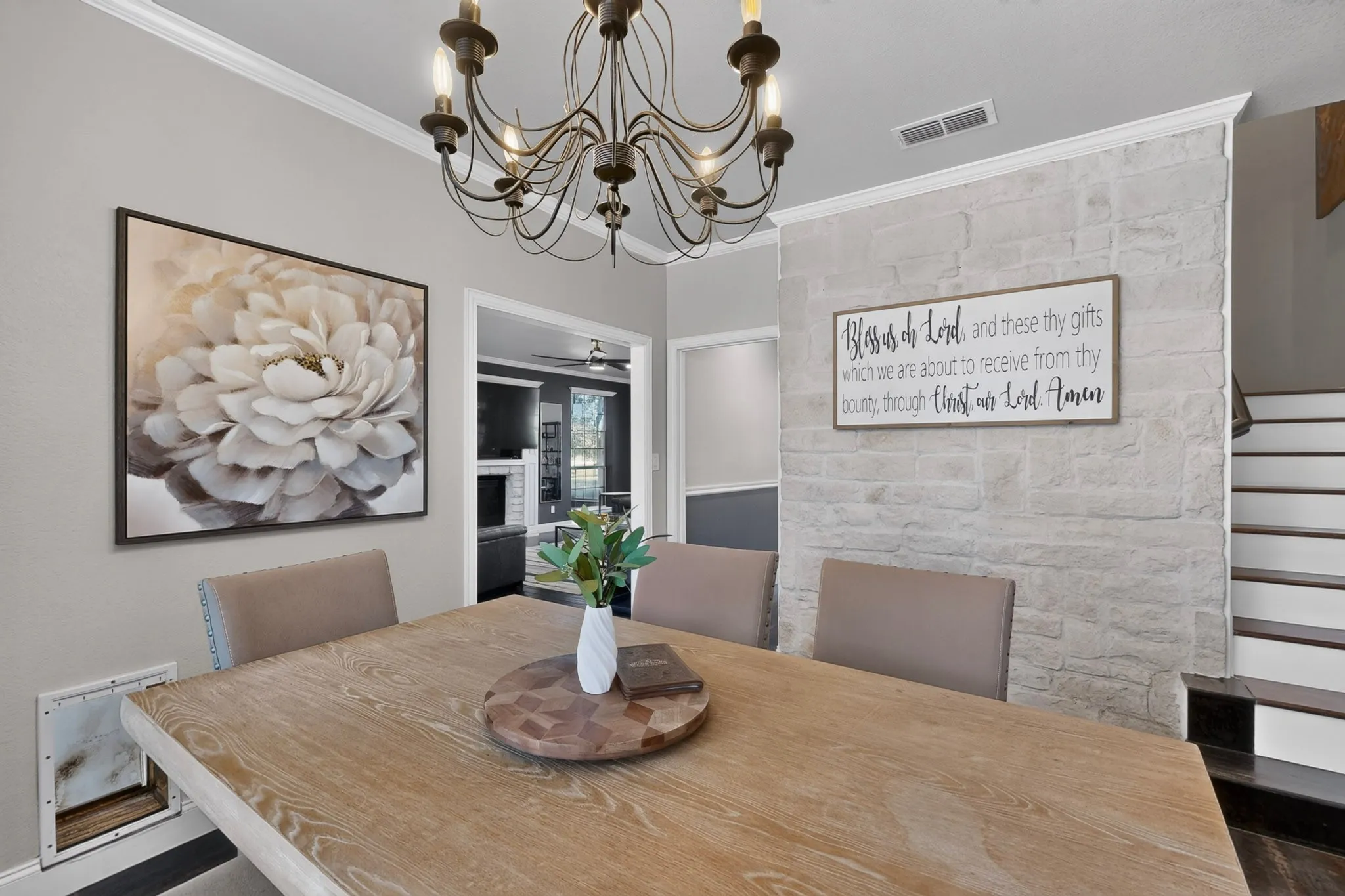 Dining area featuring a wood-finish table, a dark bronze chandelier, and a stone accent wall