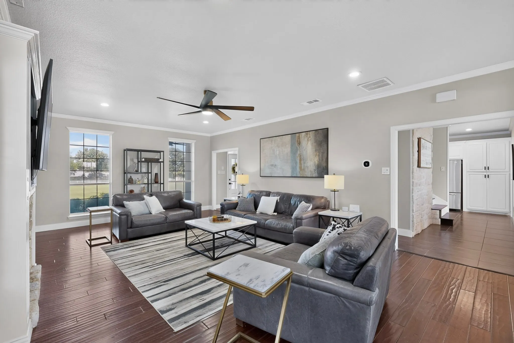 Spacious living area featuring rich wood-finish flooring, recessed lighting, and crown molding