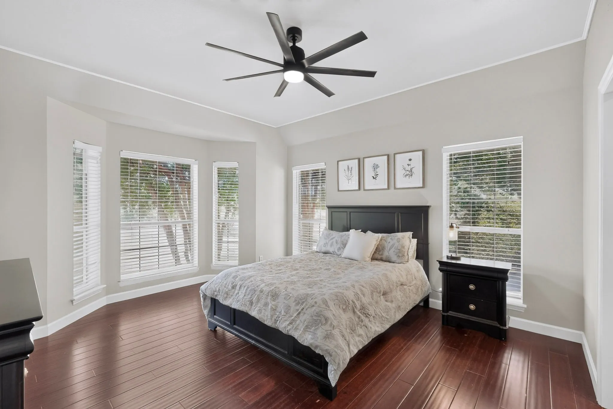 Spacious room featuring rich wood-finish flooring and a contemporary black ceiling fan