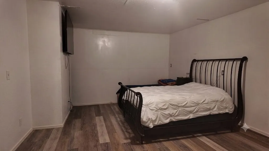 Room featuring wood-finish flooring, white painted walls, and white baseboards