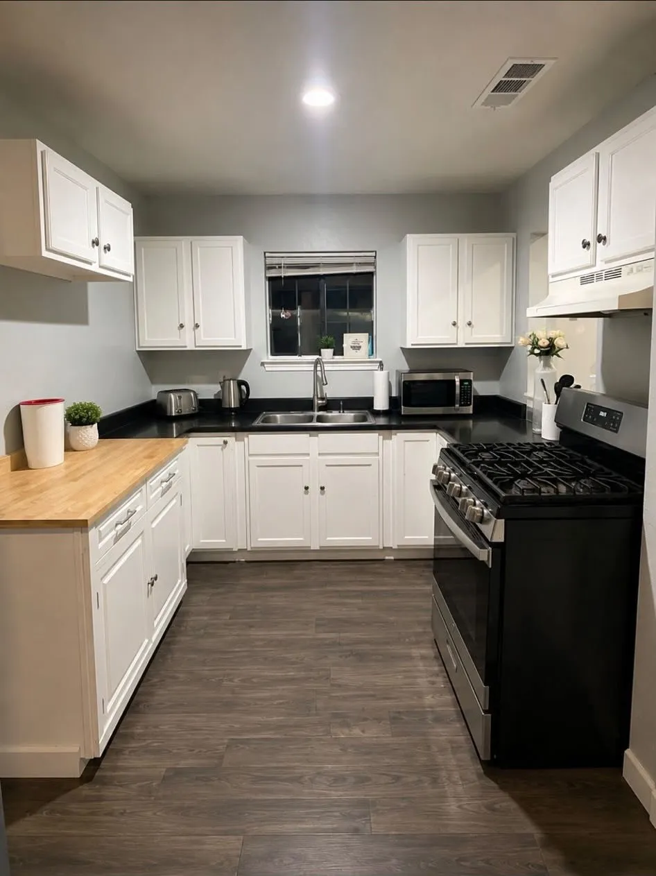 Kitchen featuring white shaker-style cabinetry, dark wood-finish flooring, a stainless steel gas range, and a dual-basin stainless steel sink