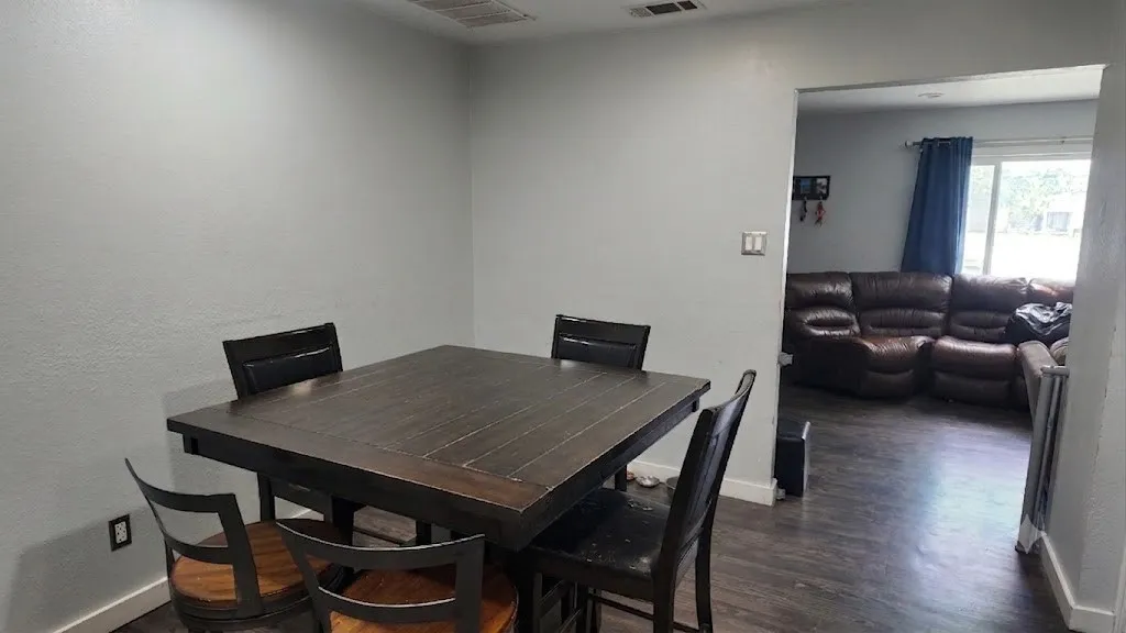 Dining area featuring light gray walls, dark wood-finish flooring, and white baseboards