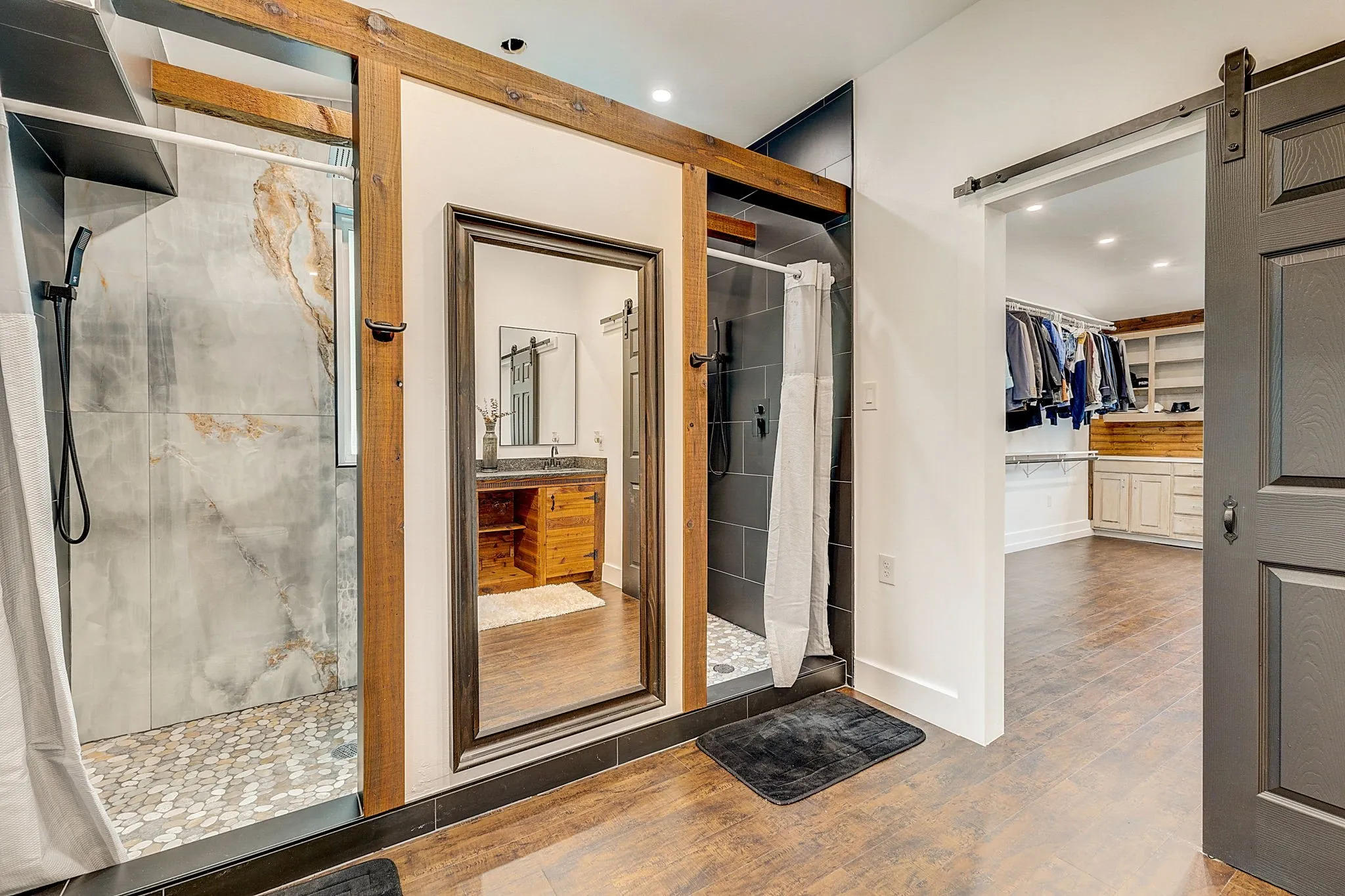 Primary Bathroom with his and her showers, hardwood flooring, a tile shower, and a large double vanity