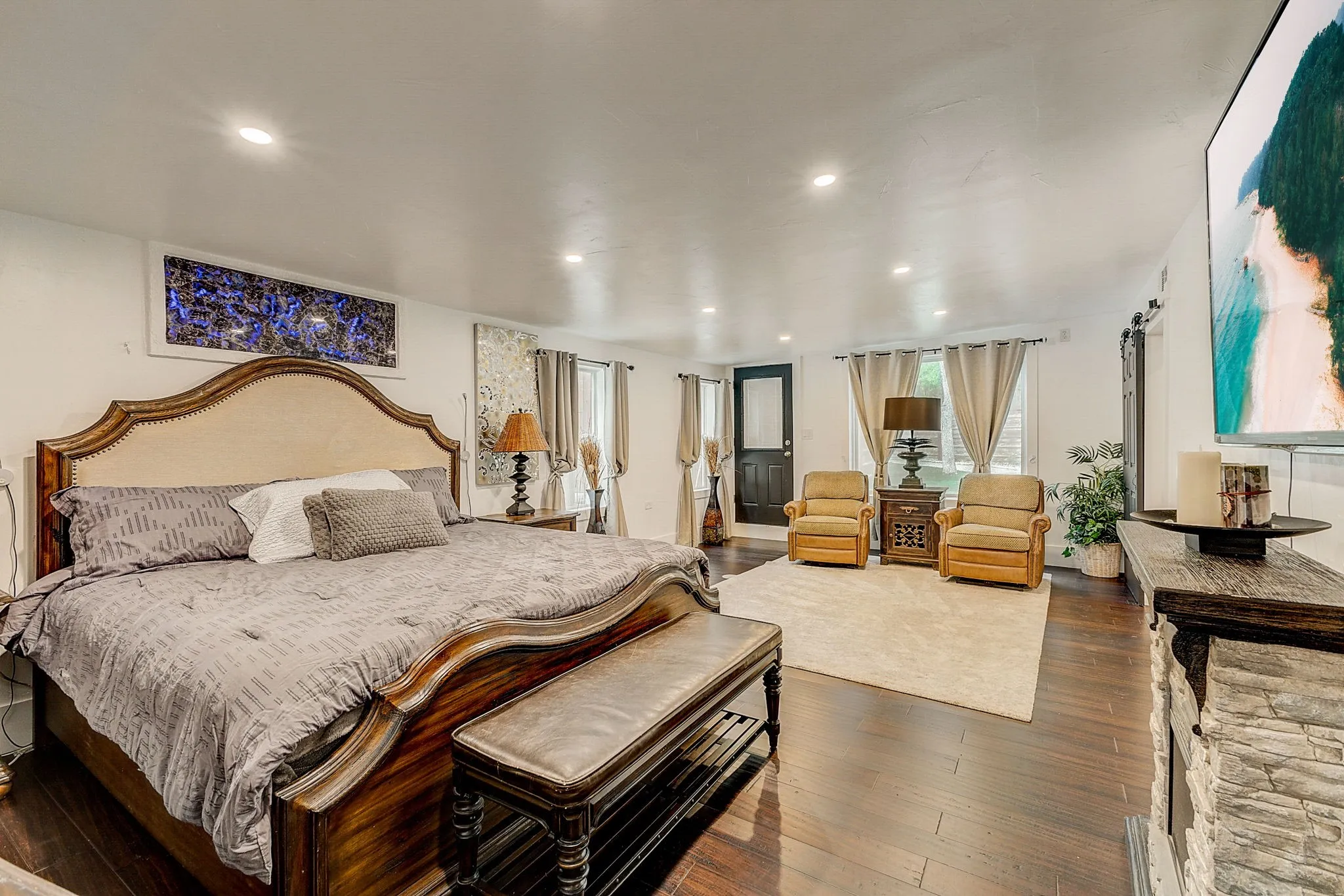 Primary Bedroom with a fireplace and a barn door, wood flooring.