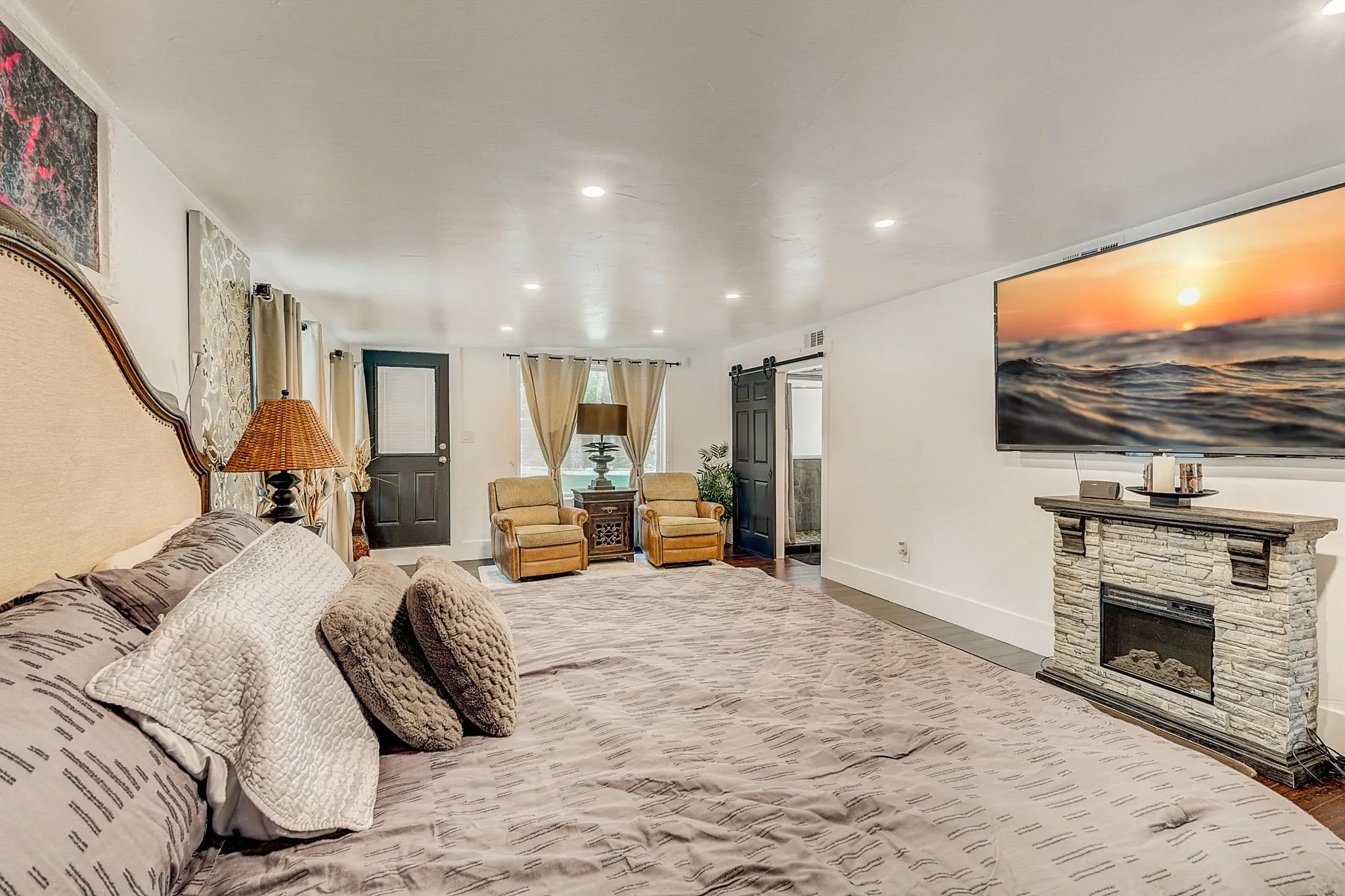 Primary Bedroom with a fireplace and a barn door, wood flooring.