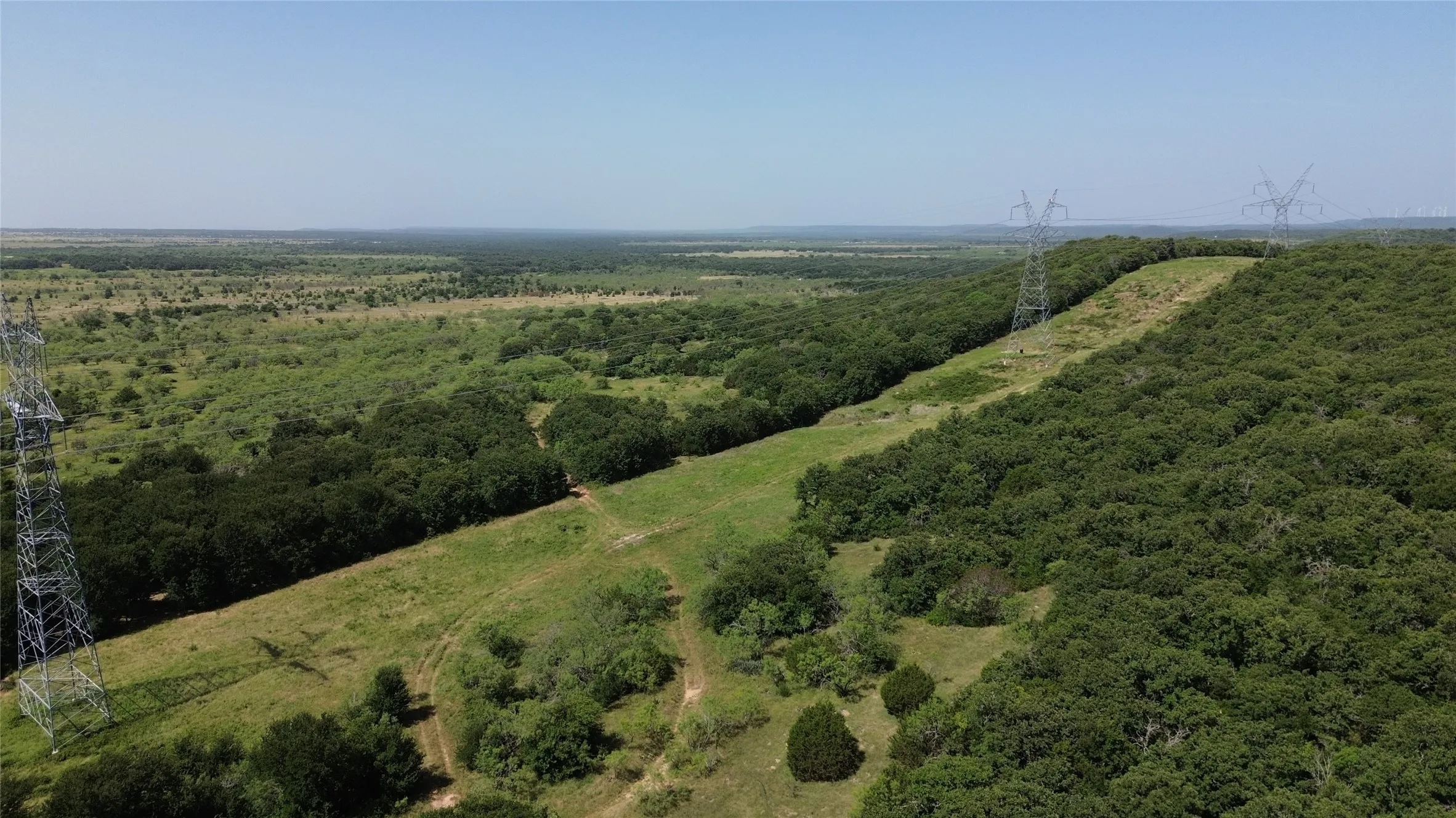 Expansive natural landscape featuring varied topography with dense tree coverage and open grassy areas
