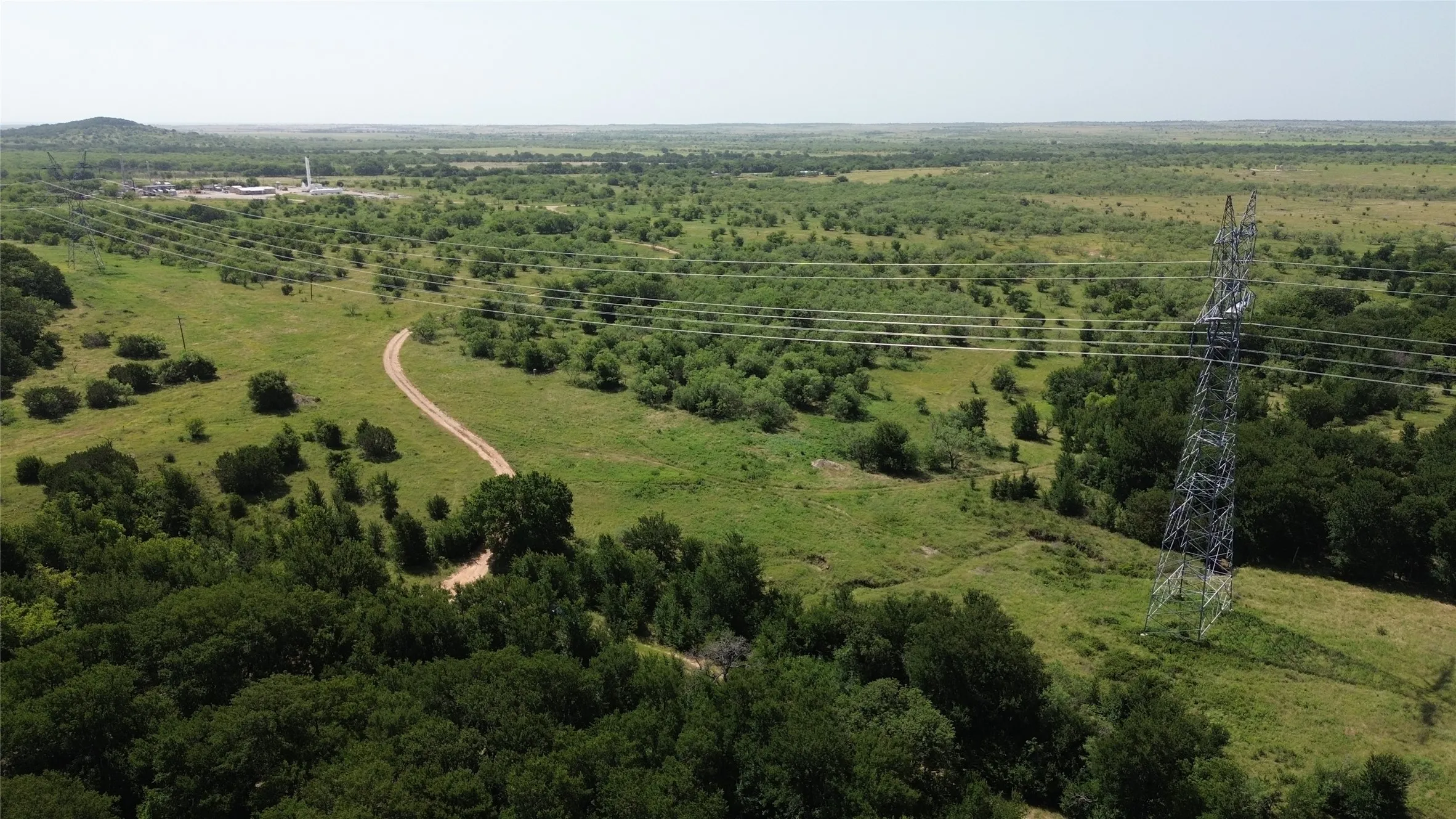 Expansive rural landscape featuring a winding dirt road and diverse vegetation