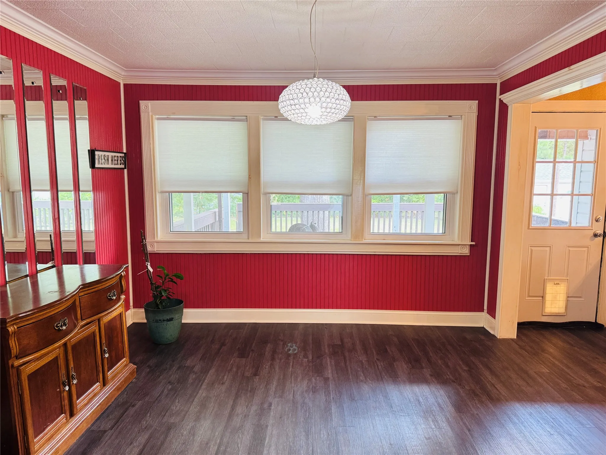 Dining space featuring a healthy amount of sunlight, baseboards, ornamental molding, and dark wood-type flooring
