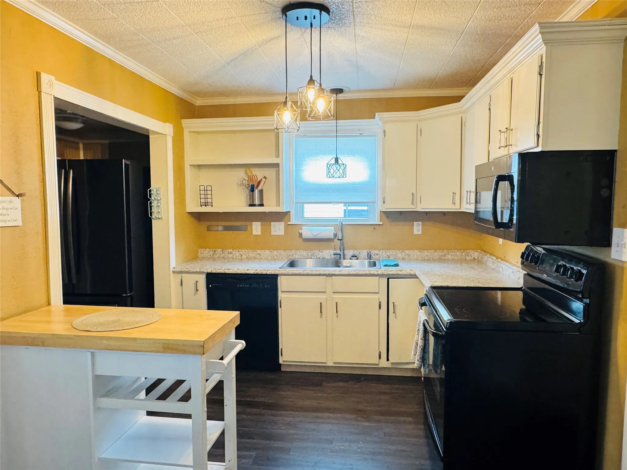 Kitchen with decorative light fixtures, black appliances, white cabinetry, open shelves, and a sink