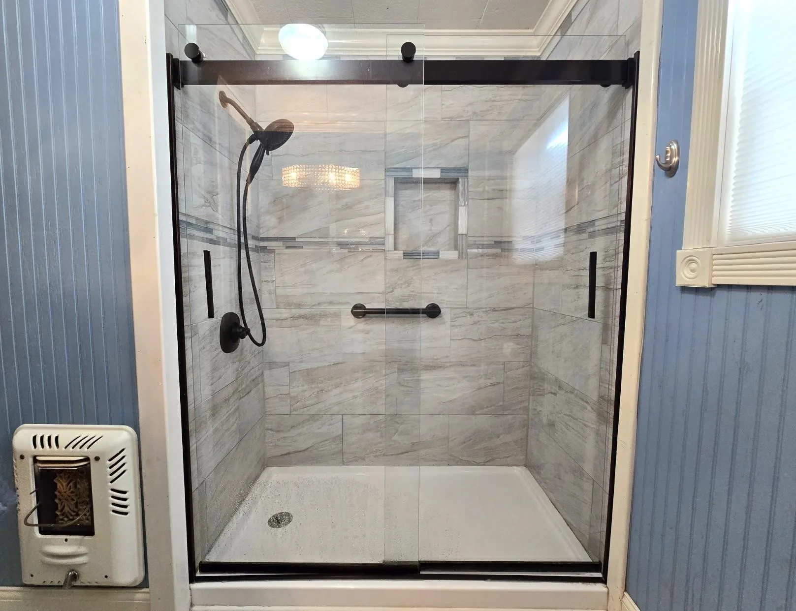Bathroom with working wall heater and newer shower