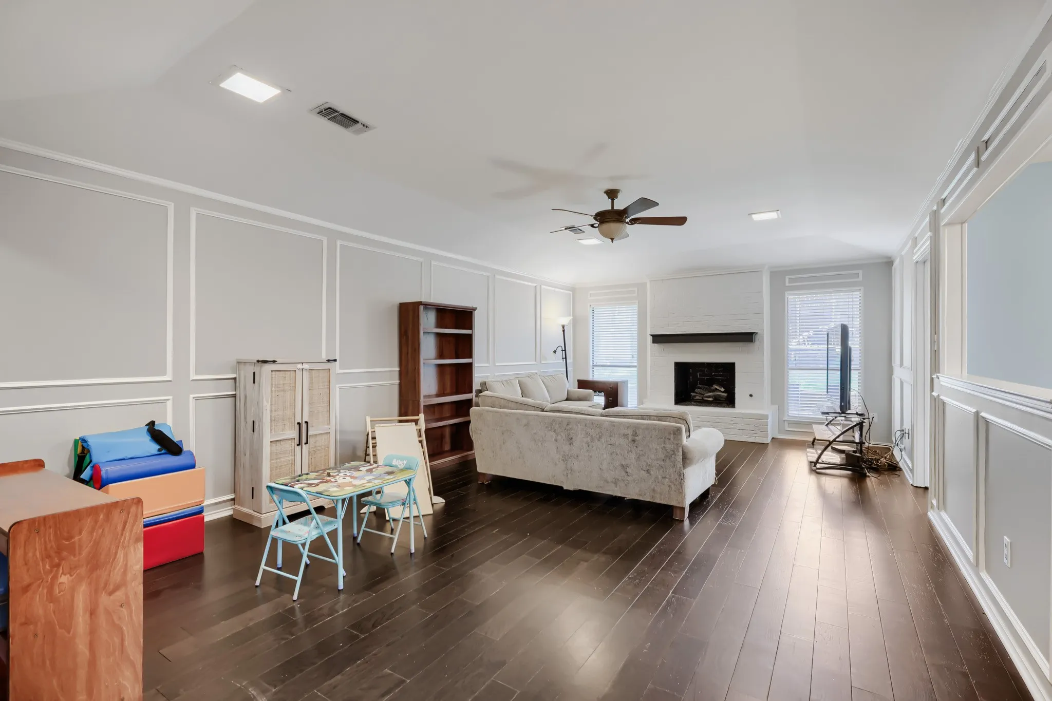 Expansive living area featuring rich wood-finish flooring and decorative wall paneling