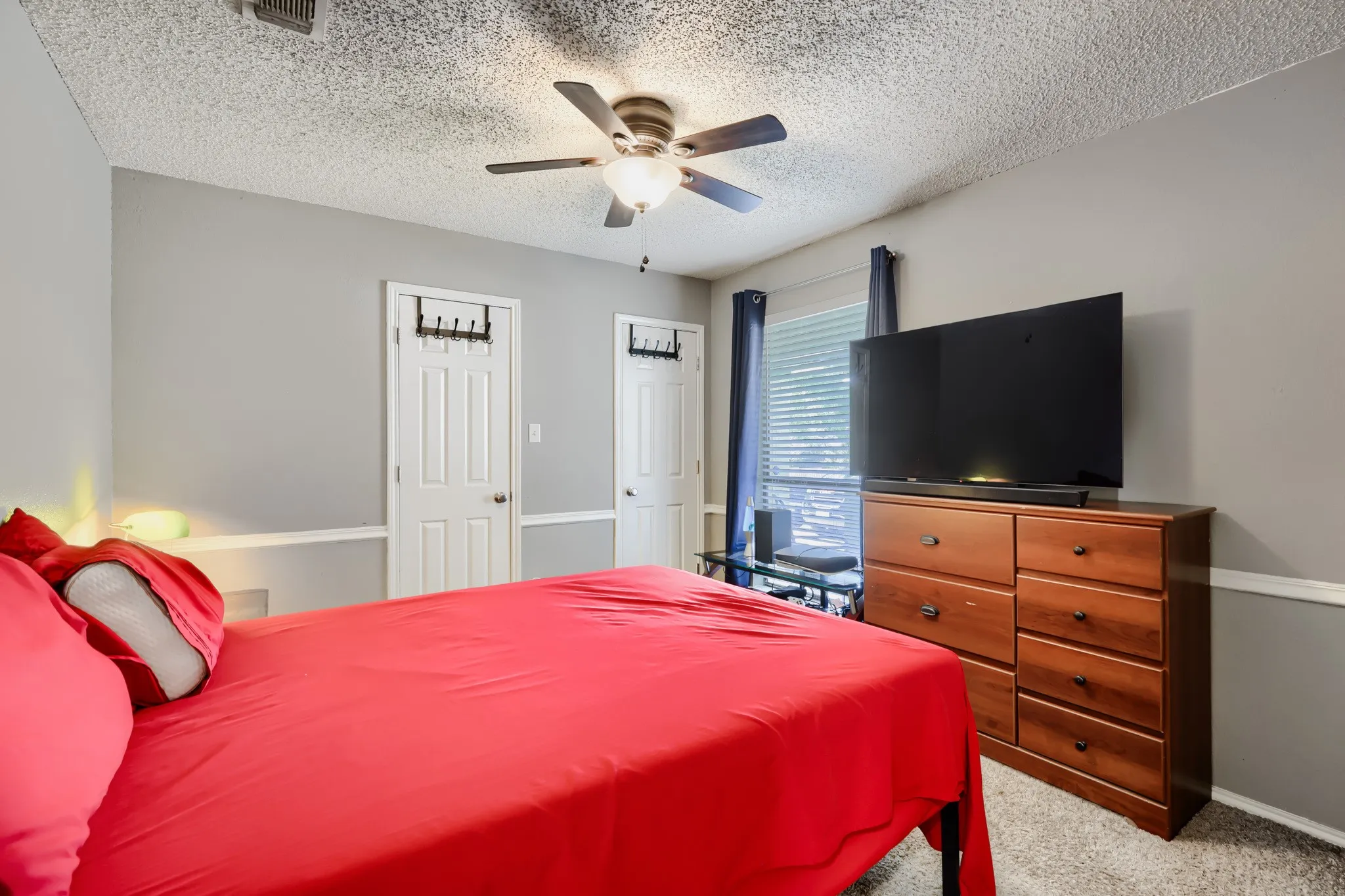 Carpeted bedroom featuring light gray walls, white trim, and a ceiling fan with integrated lighting