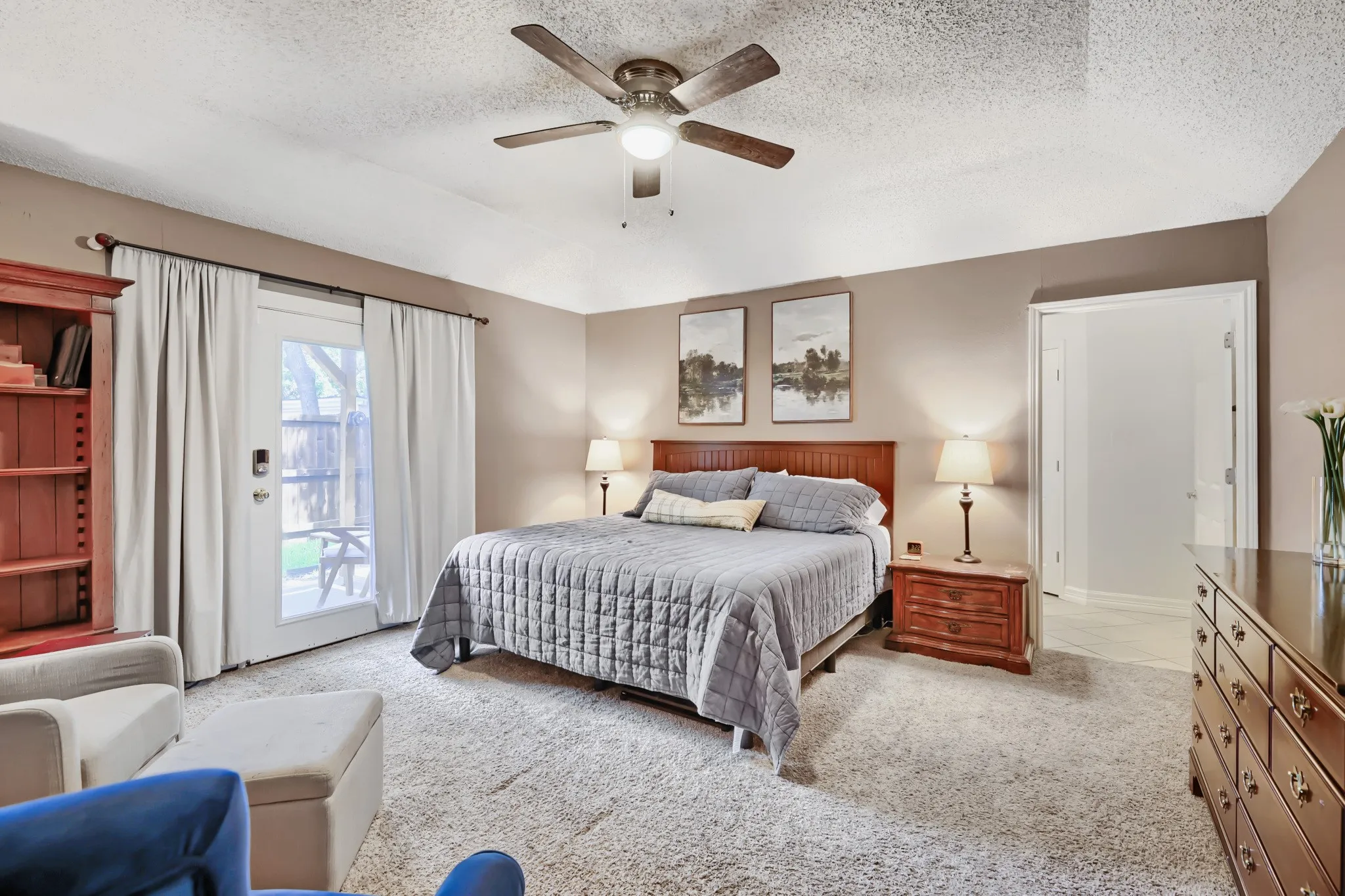 Carpeted room featuring a ceiling fan with integrated lighting, direct outdoor access via a white door, and neutral-toned walls