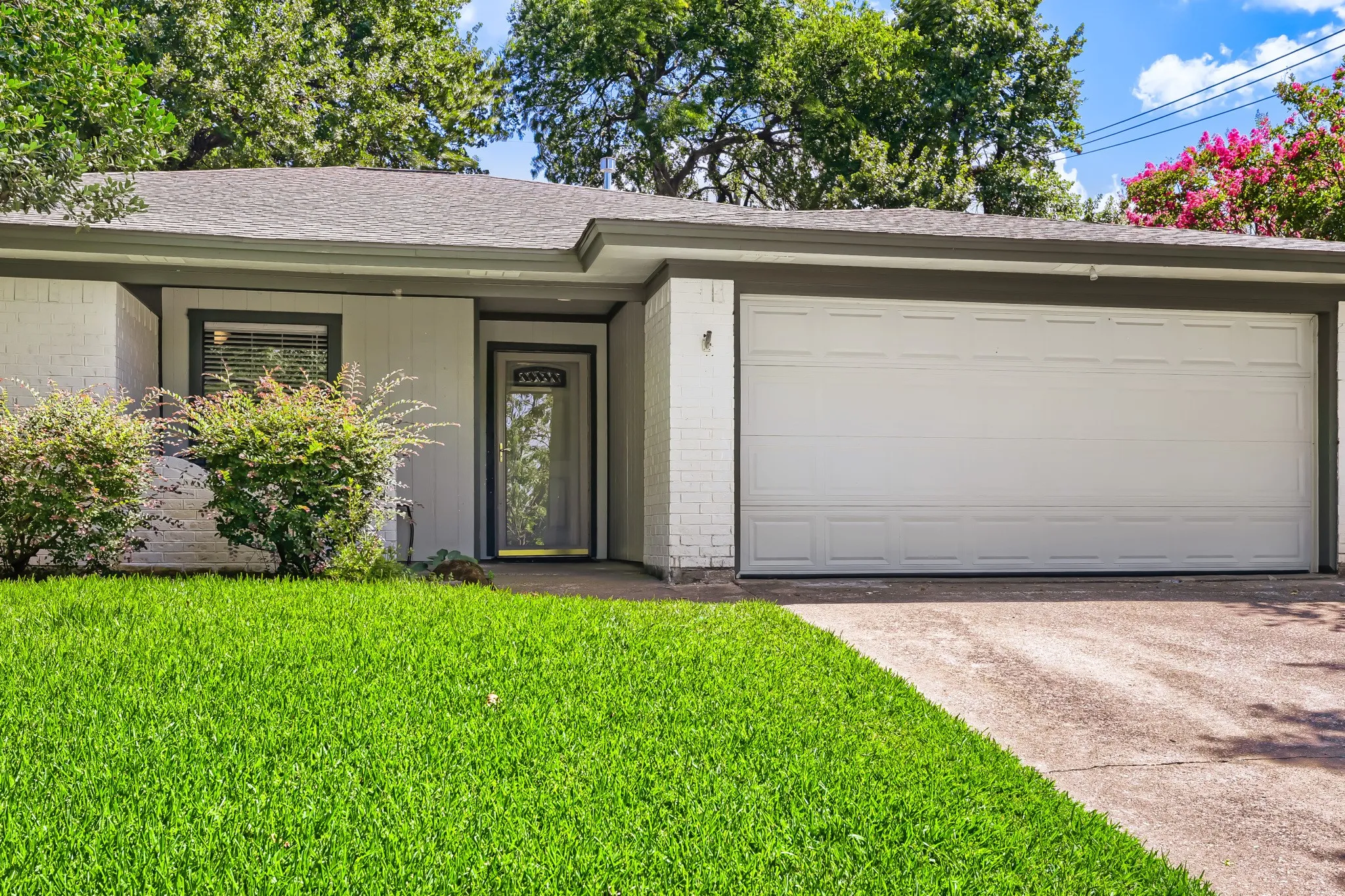 White brick exterior with dark trim and a two-car garage