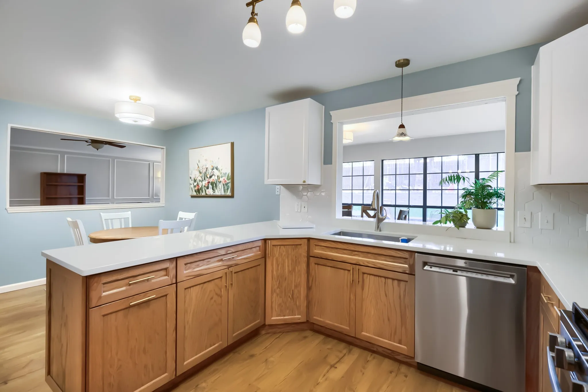 Kitchen featuring light wood-finish flooring, white countertops, coordinating white upper cabinetry, and natural wood-finish lower cabinetry