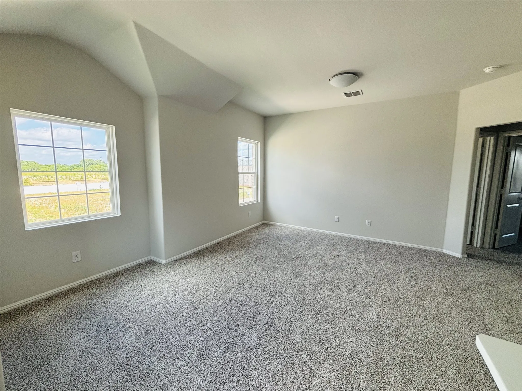 Carpeted empty room featuring a smoke detector and vaulted ceiling