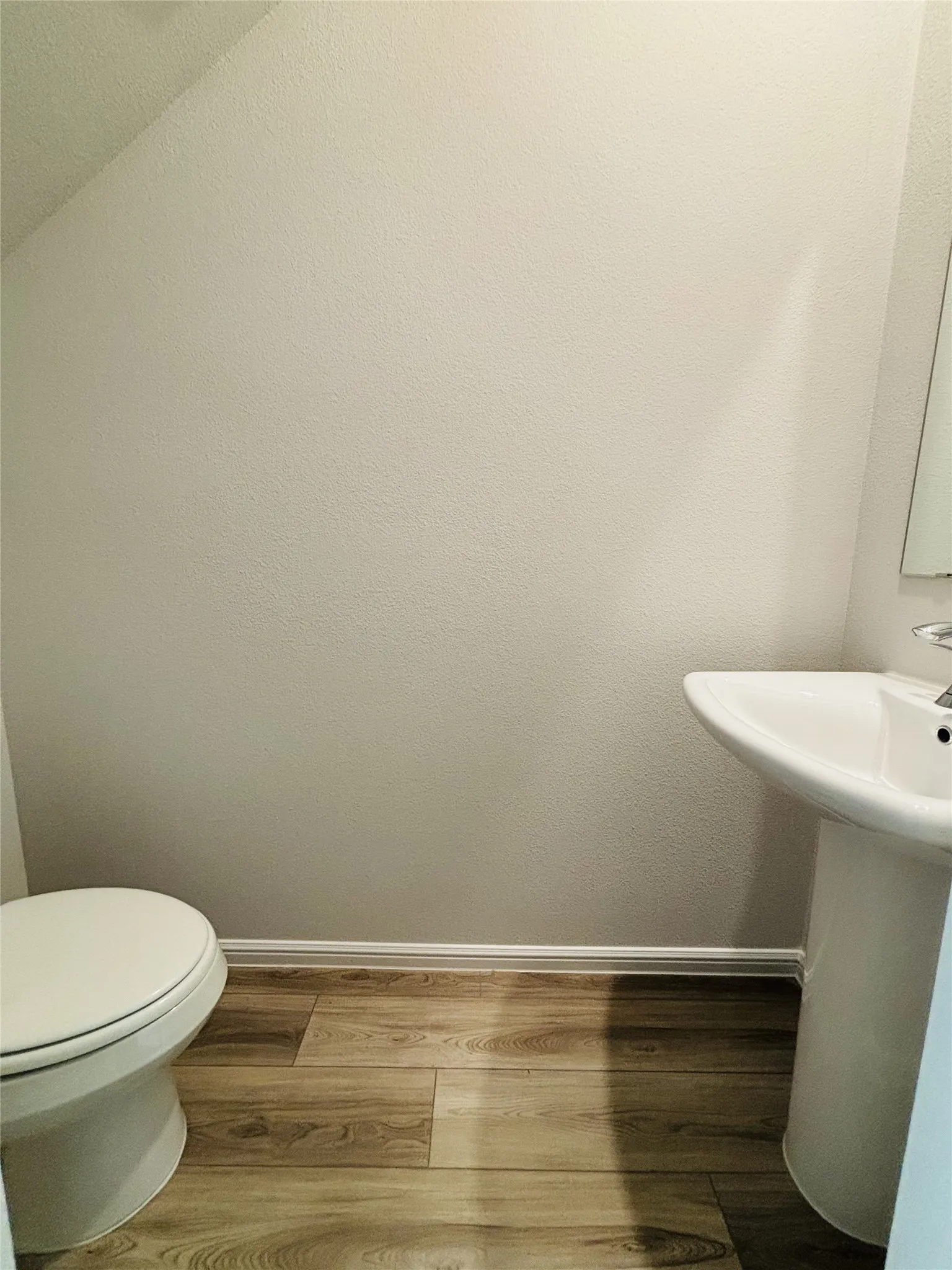 Half bathroom with baseboards and wood finished floors